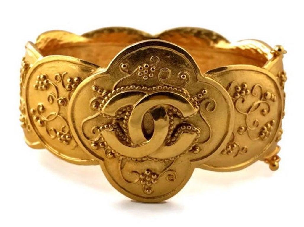 Vintage CHANEL Baroque Logo Hinged Bracelet Cuff

Measurements:
Height: 1 6/8 inches (4.5 cms)
Inner Circumference: 7 2/8 inches (18.5 cms)

Features:
- 100% Authentic CHANEL.
- Embossed CC logo at the centre.
- Accentuated with embossed grapes and