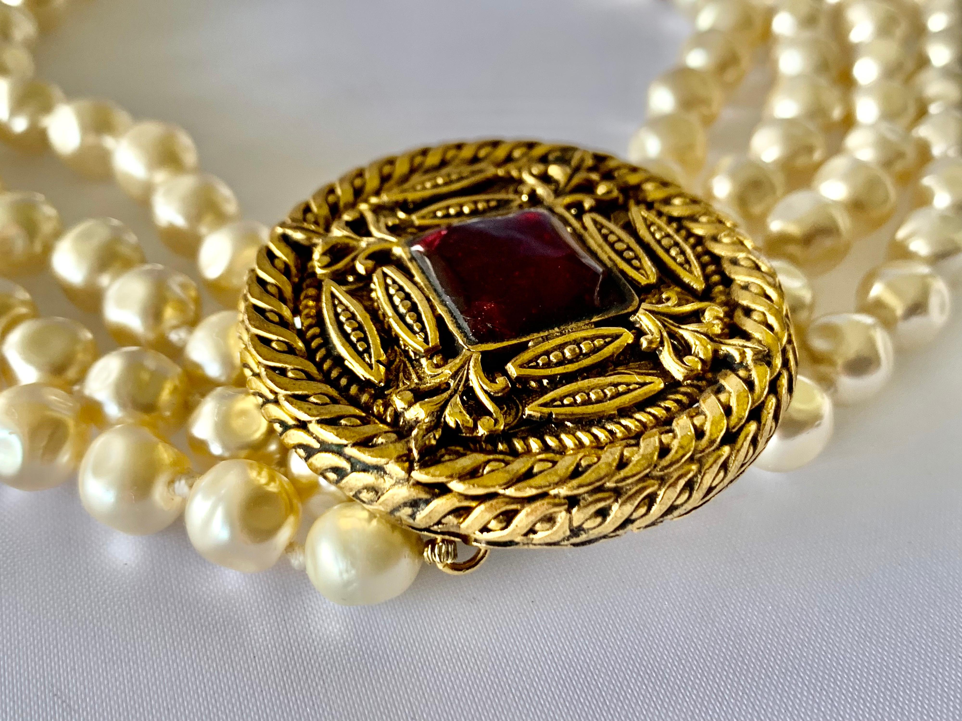 Collier vintage Coco Chanel - composé de huit rangs de grosses perles baroques avec un grand médaillon rond doré en métal doré avec un gripoix rouge en pate de verre.  cabochon en verre fondu coulé. Signé Chanel 1984. 