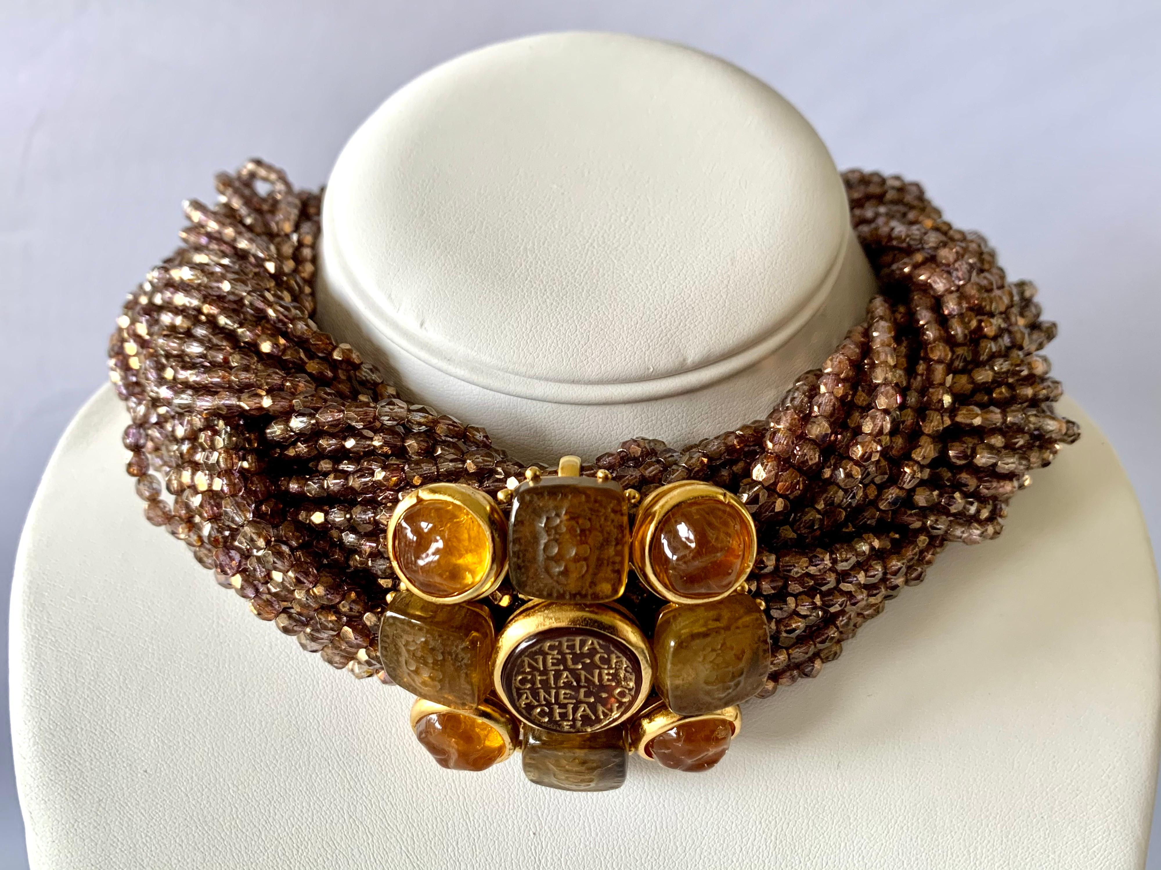 Beeindruckende und seltene Vintage Chanel Haute Couture Halskette - Choker bestehend aus drei geflochtenen Strängen aus schillernden bronze/lila facettierten Glasperlen. In der Mitte der großen Halskette befindet sich ein großes vergoldetes