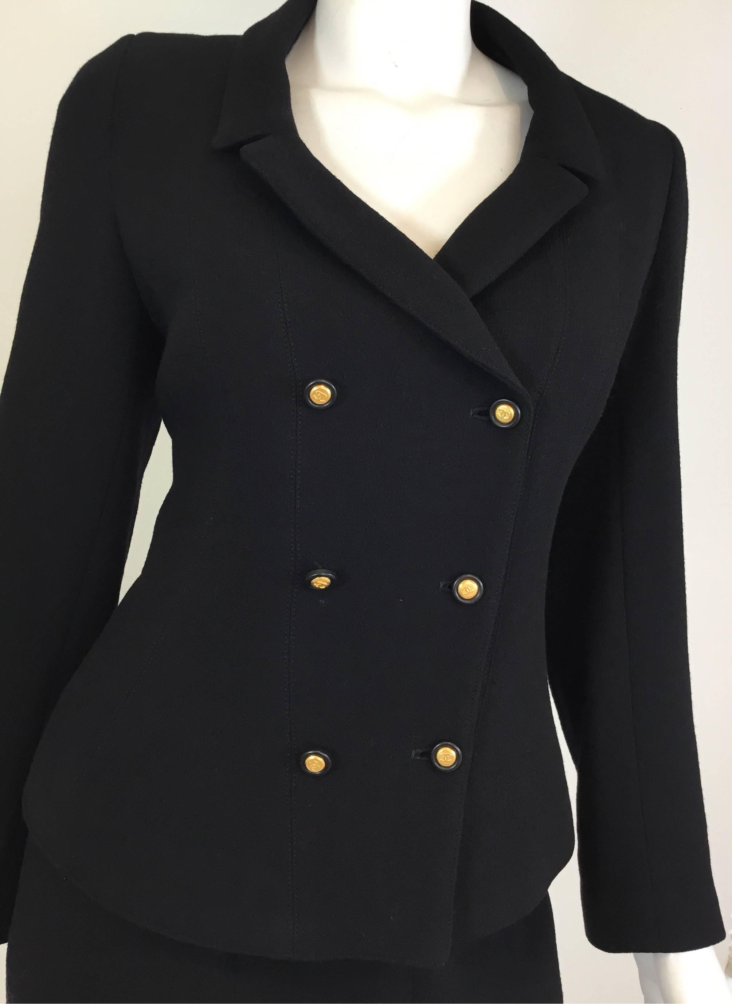 Chanel vintage skirt suit in black with signature black gold button fatsenings throughout. Jacket has button front closures and also on the cuffs of the sleeve. Skirt has a back zipper fastening and buttons at the hem. Suit is fully lined in a silk