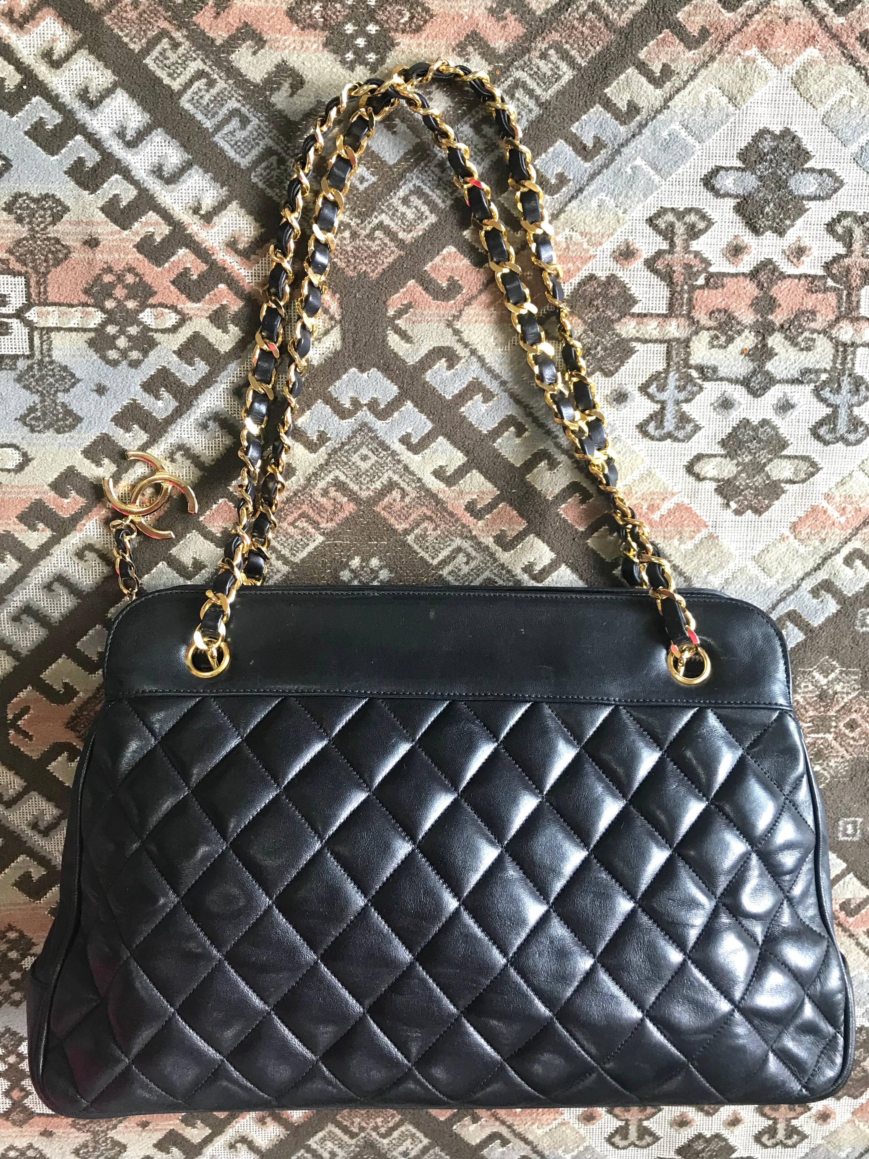 1980-1990s. Vintage CHANEL black lambskin large tote bag with gold tone chains and jumbo CC charm to the LAMPO zipper. Classic purse.

Vintage CHANEL black lambskin large trapezoid shape shoulder bag with gold tone chains and jumbo CC charm to the