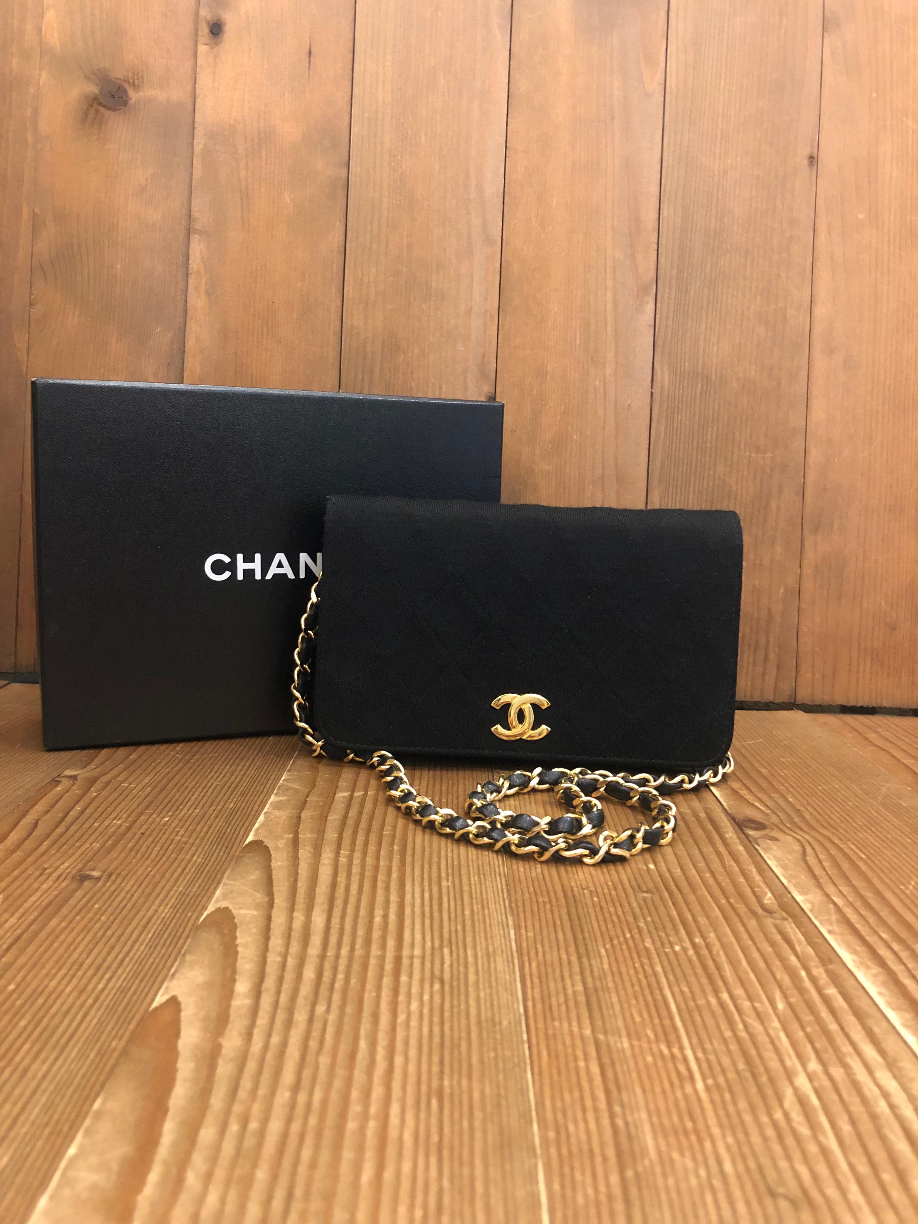 This 1980s vintage CHANEL chain shoulder bag is crafted of black diamond quilted jersey and gold toned hardware featuring a gold toned chain interlaced with black lambskin leather. Front flap snap closure opens to a lambskin leather interior in