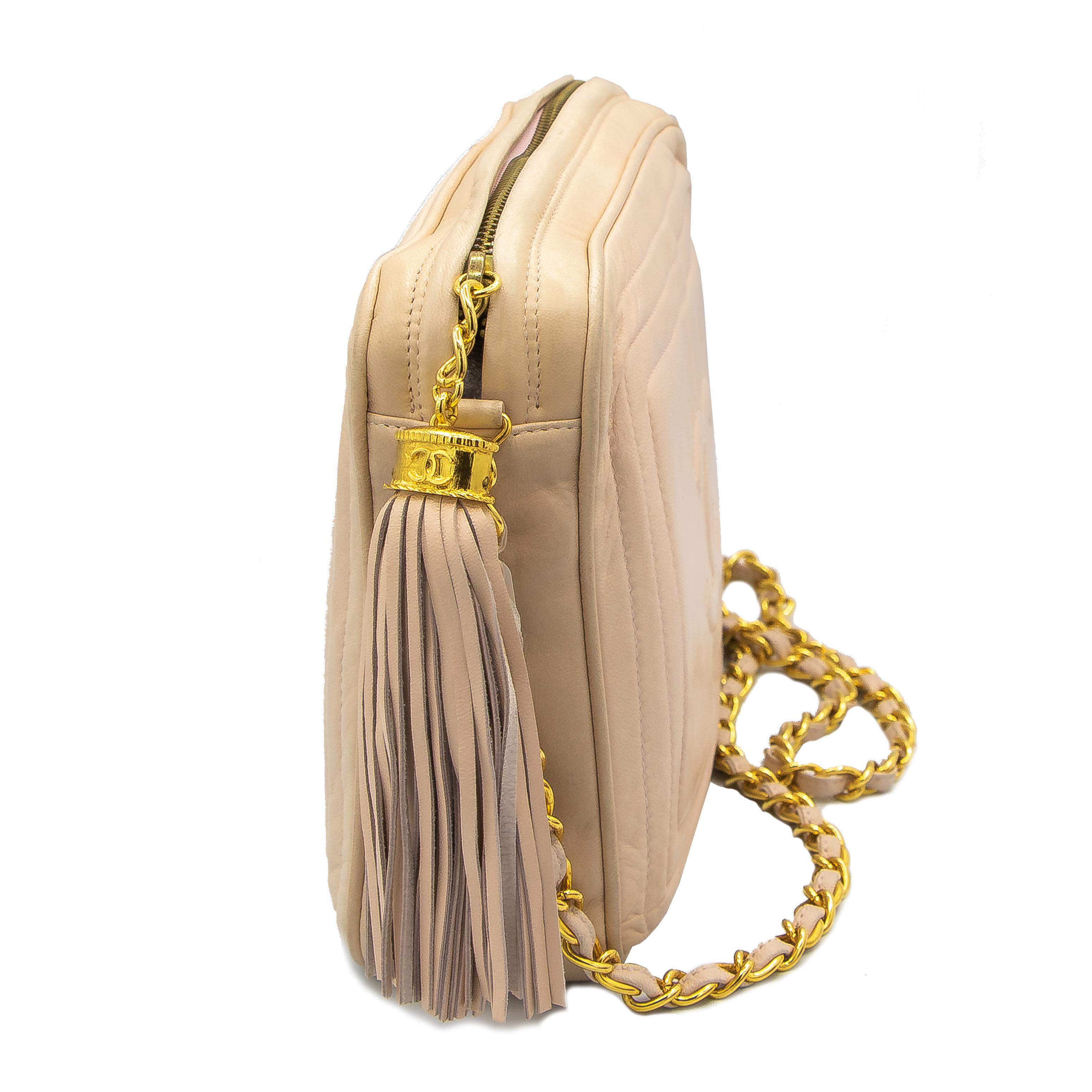 Beautiful Crossbody Chanel bag with one main pouch and a small zippered section. Yellow gold colored hardware, and a yellow gold colored chain with matching leather woven between it. The main zipper has a Coco Chanel tassel with nude leather. Signed