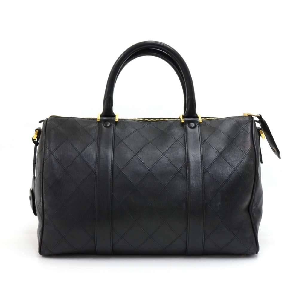 Chanel Boston travel bag in black quilted lambskin leather. Main area is secured with zipper. Inside is lined with black leather and has 2 zipper pockets and a very spacious interior. Comes with a Gold-tone Chanel tag, padlock with 2 keys, and a