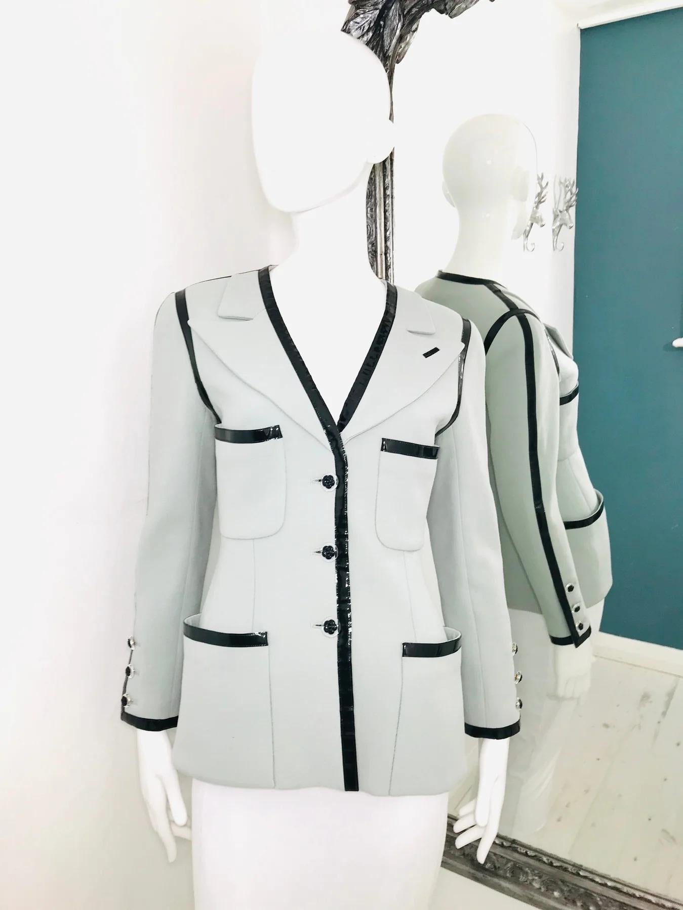 Vintage Chanel Boutique Pale Blue Jacket with Black Patent Leather Trim

Long sleeves. Four front pockets.Plastic buttons with Camellia at the front and three on the each sleeve. Blue lining with CC logo printed Gold chain at the bottom on the