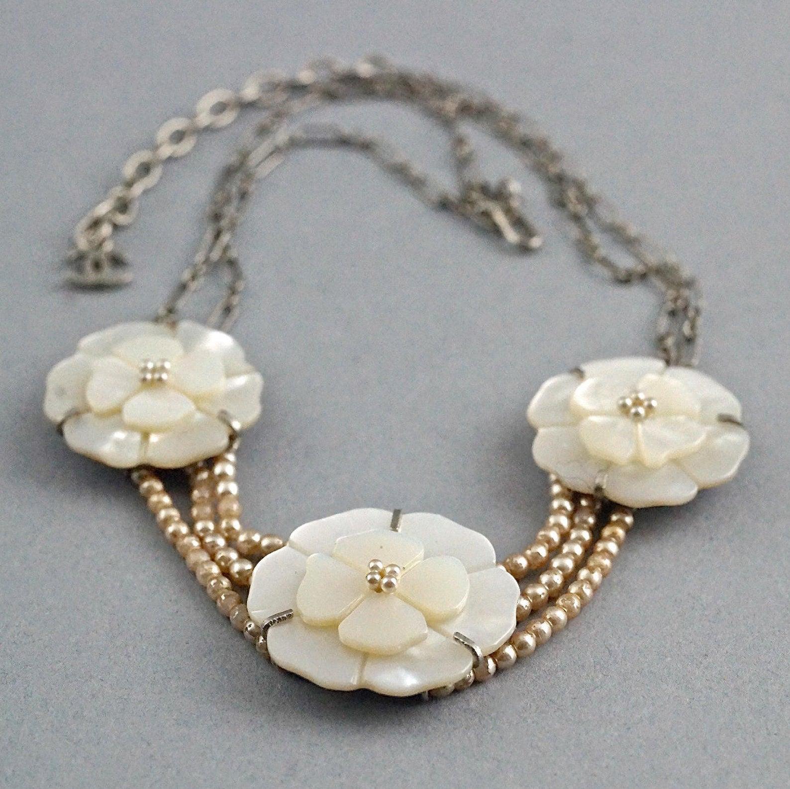 Vintage CHANEL Camellia Mother of Pearl Flower Multi Strand Necklace

Measurements:
Large Camellia: 1.10 inches (3.1 cm)
Small Camellia: 1.06 inches (2.7 cm)
Length: 13.97 inches to 16.14 inches (35.5 cm to 41 cm)

Features:
- 100% Authentic