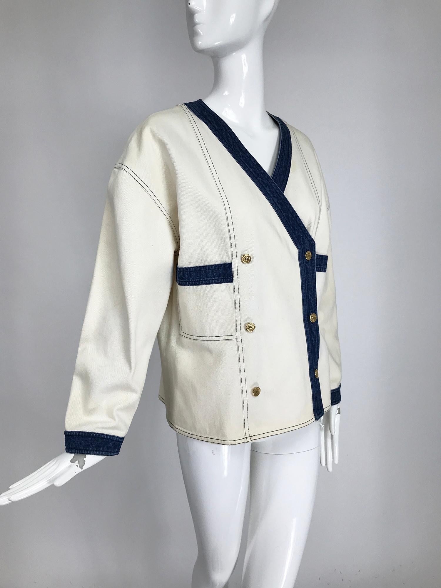 Vintage Chanel off white canvas and blue denim trimmed double breasted jacket from the 1980s. V neckline, long sleeves, jacket closes with Chanel gold logo buttons at the front. Front patch pockets. Unlined, with flat felled seams. Top stitch
