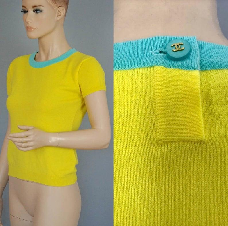 Vintage CHANEL Cashmere Knit Yellow Turquoise Trim CC Logo Button Top

Measurements taken laid flat, please double bust, waist and hips:
Shoulder: 14.96 inches (38 cm)
Sleeves: 4.72 inches (12 cm)
Bust: 16.92 inches (43 cm)
Waist: 15.35 inches (39