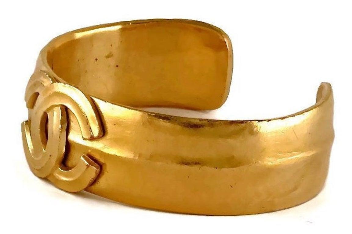 Vintage CHANEL CC Logo Cuff Bracelet

Measurements:
Height: 6/8 inch (1.90 cm)
Circumference: 7 inches (17.78 cm)
Opening:1 3/8 inches (3.49 cm)

Features:
- 100% Authentic CHANEL.
- CC logo overlay at the centre.
- Gold tone.
- Signed CHANEL 95 CC