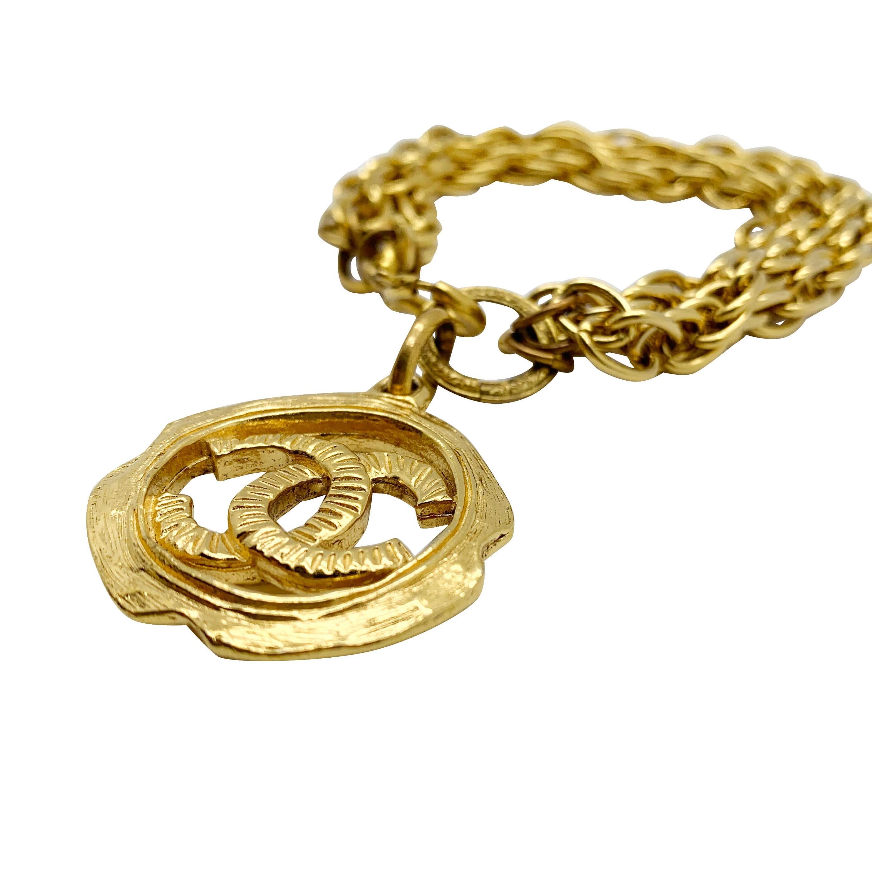 Our Vintage Chanel Logo Charm Bracelet. A stunning statement charm bracelet from the House of Chanel hailing from the uber glam 1980s. The large interlocking CC motif medallion dropping away from a torsade effect trio of fancy link chains. A very