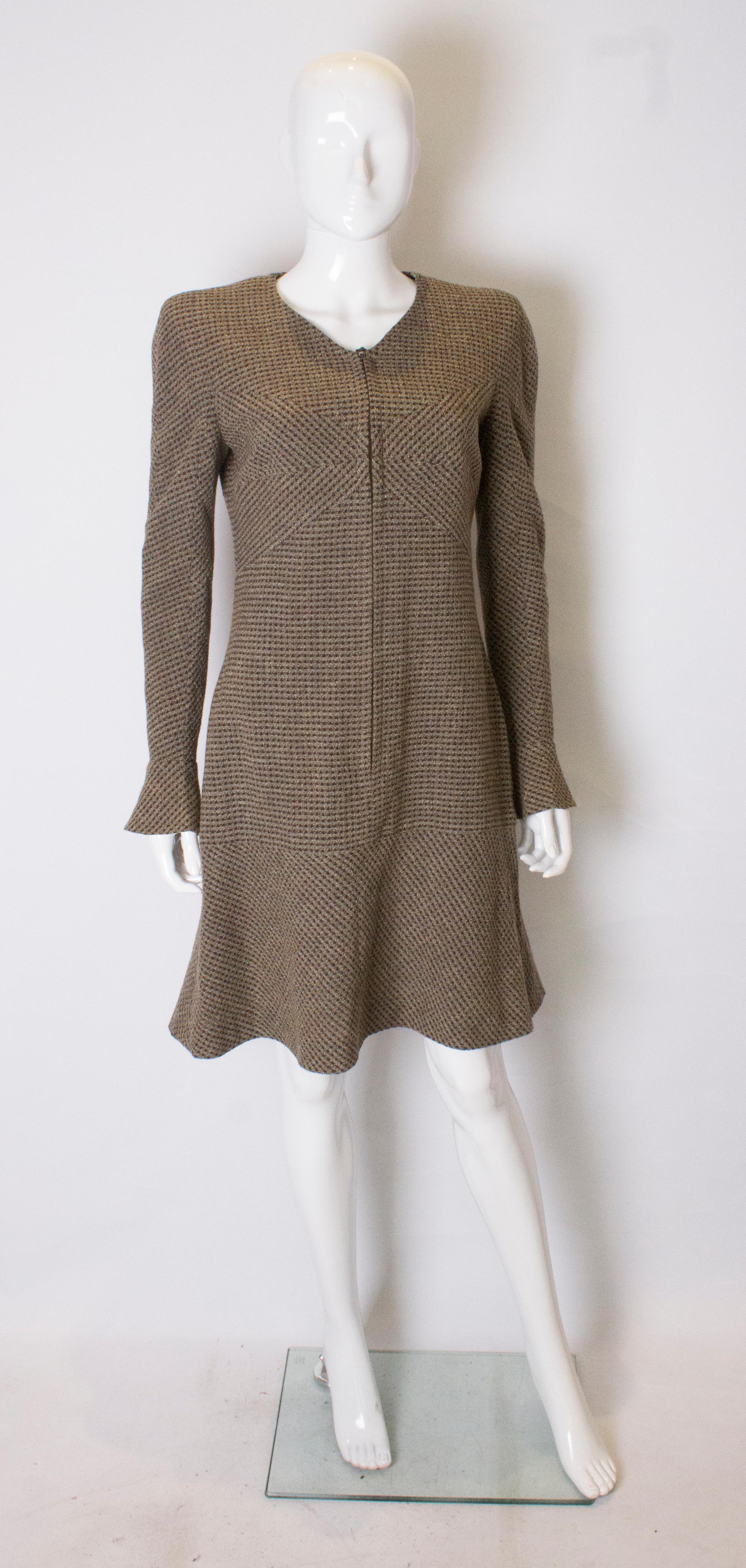 A chic and easy to wear coat dress by Chanel. From the 1997 collection, the coatdress is in a wool outer fabric, in an brown and blue mix with a silk lining. It has a v neckline,  zip opening at the front, a drop waist and frill at the hem. It comes