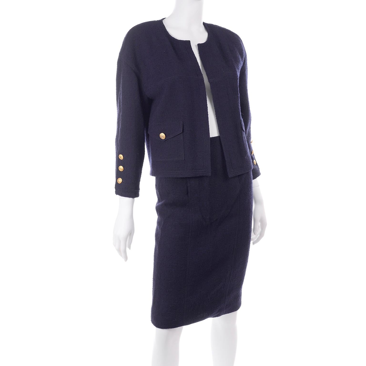 This classic vintage Chanel Boutique two piece suit has a slim fit skirt and a short boxy open front blazer or jacket . This suit is made with the quality you would expect from Chanel, with chain detail at the hem of the lining of the jacket, silk