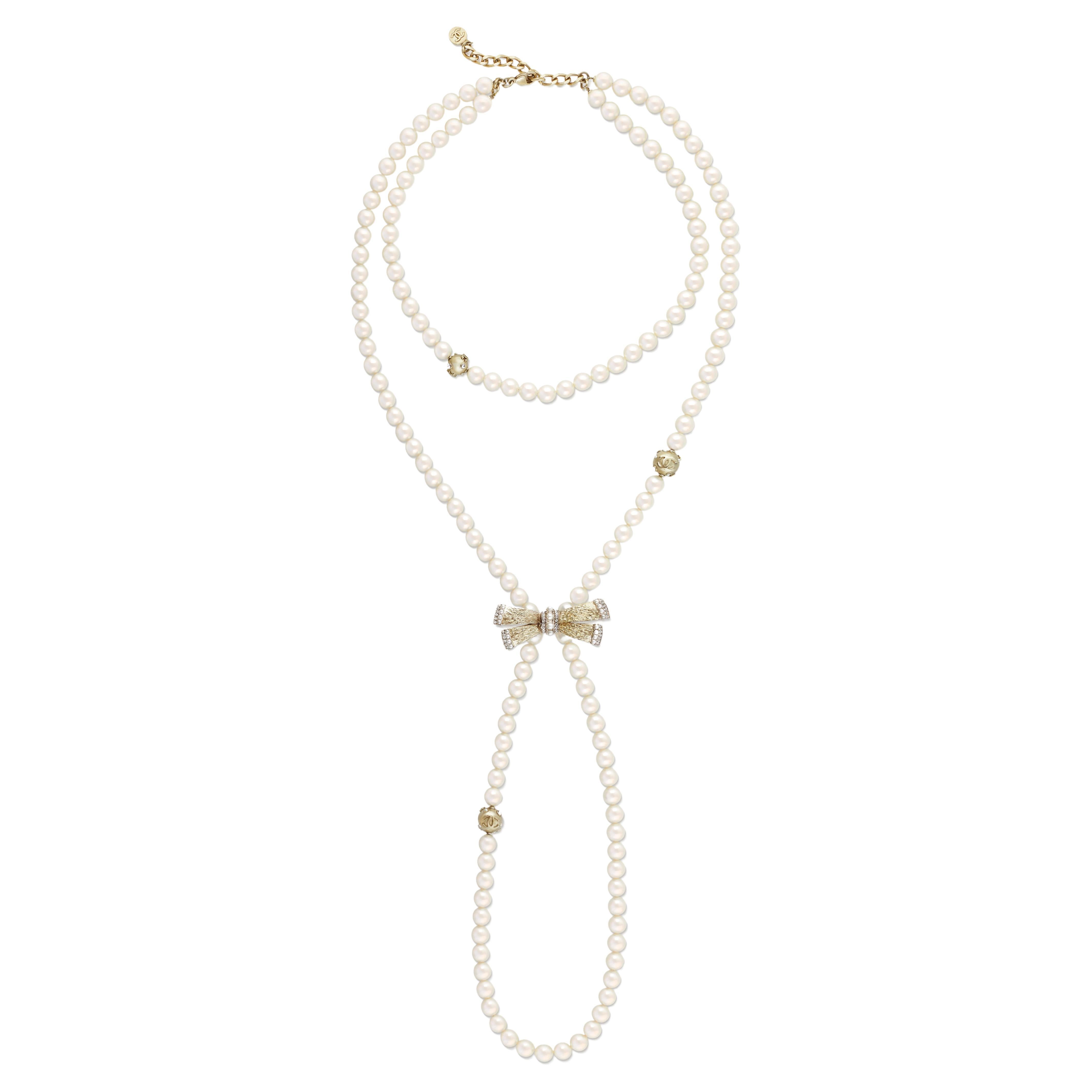Chanel double strand faux pearl sautoir necklace with bow and CC logo stations, from Spring/Summer 2006. This classic Chanel necklace features a double strand of faux pearls, one choker length and the other long and bound with a crystal and