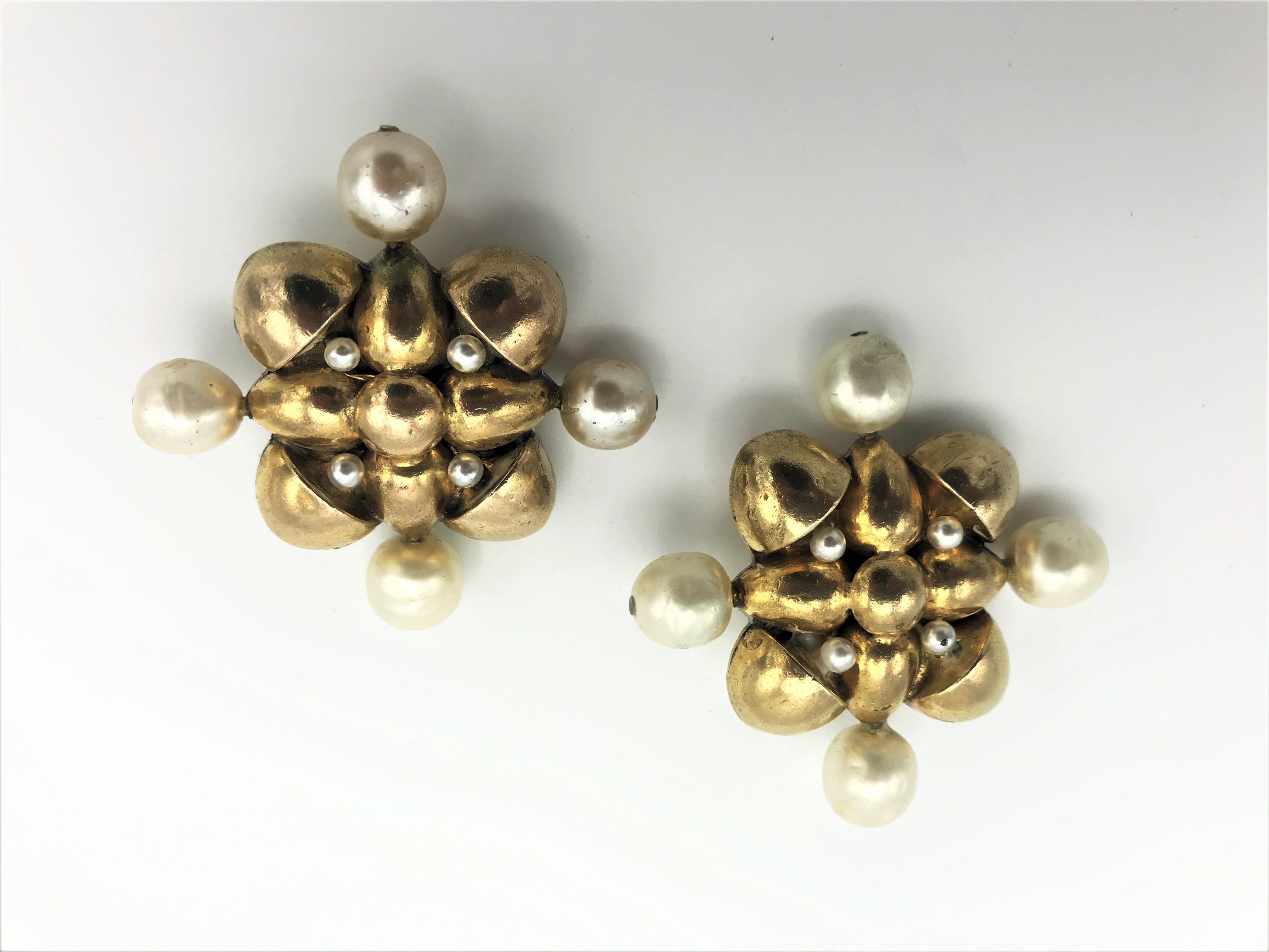 Sehr frühe Ohrclips von Chanel aus den 70/80er Jahren in Form eines Kreuzes, flankiert von 4 falschen Barockperlen.
Maße: 4 Kunstperlen 1 cm Durchmesser, Breite mit Perlen 5 x 5 cm, Breite des Goldteils 3,2 x 3,2 cm. Guter Zustand  