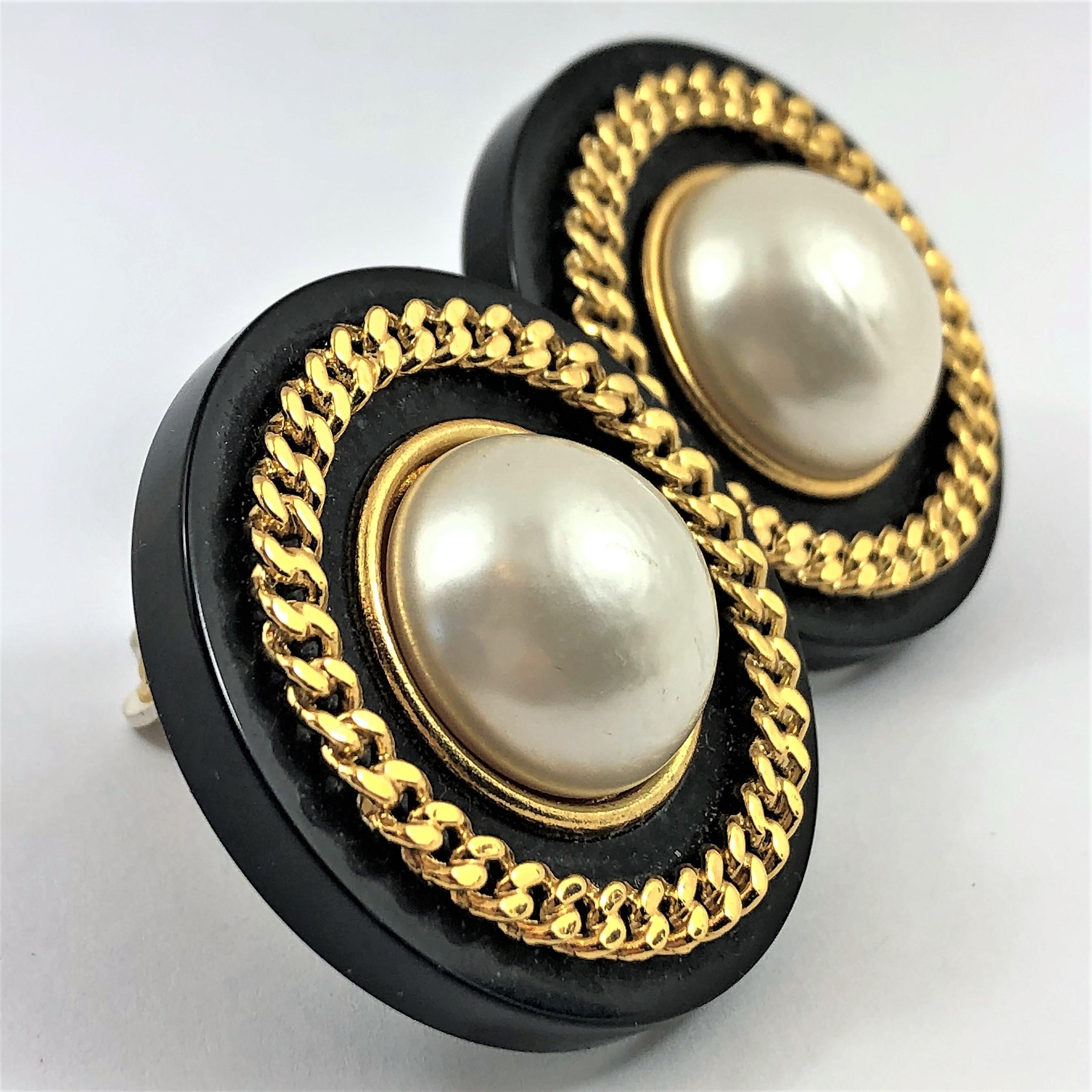 Vintage Chanel clip on earrings 1 5/8 Inch diameter, Black Resin background with large faux pearl in the center,  surrounded by gold tone chain. Part of Chanel's Season 28 
from 1991. Classic Chanel. large size yet still very tailored. Marked Chanel