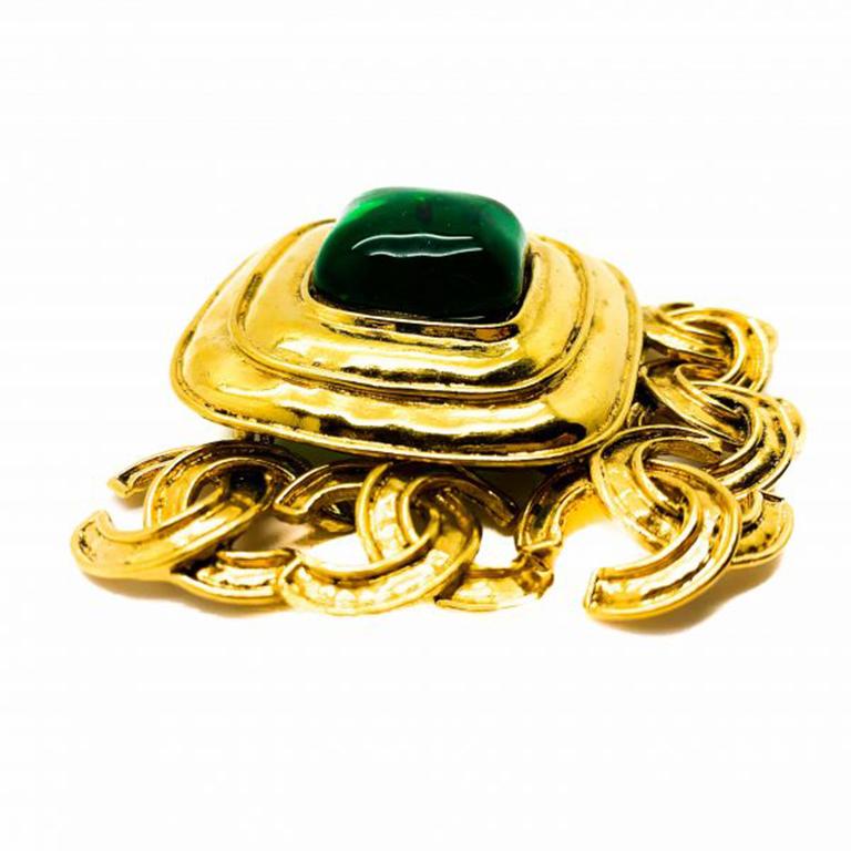 A mesmerising Vintage Chanel Gripoix CC Brooch. Featuring a sublime rounded square of emerald pâte de verre sitting magnificently in a bold square of 18ct gold plated metal. The exceptional finishing touch of five interlocking CC logo drops serving