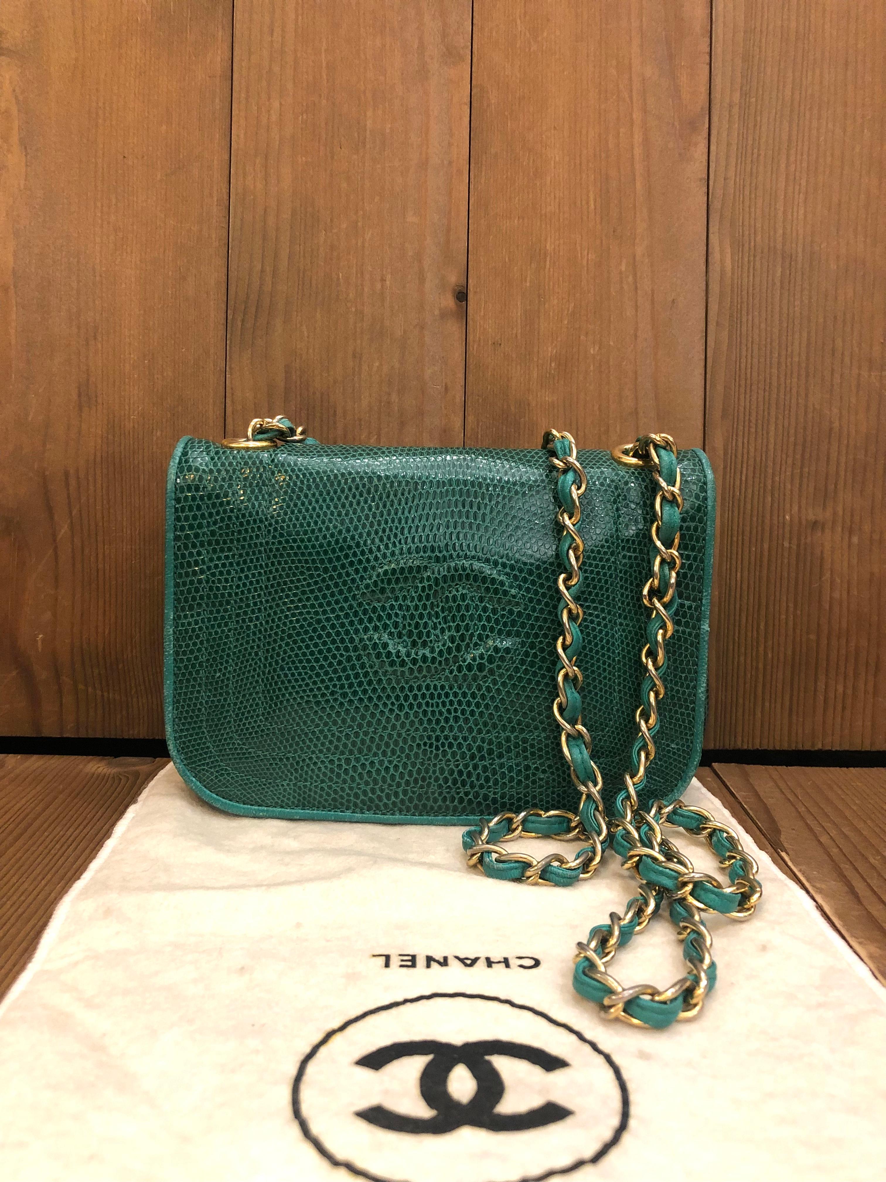 This vintage CHANEL mini flap bag is crafted of lizard skin leather in emerald green centered an embossed CC logo. This flap bag features a gold toned chain interlaced with green lambskin leather. Front flap magnetic snap closure opens to a lambskin