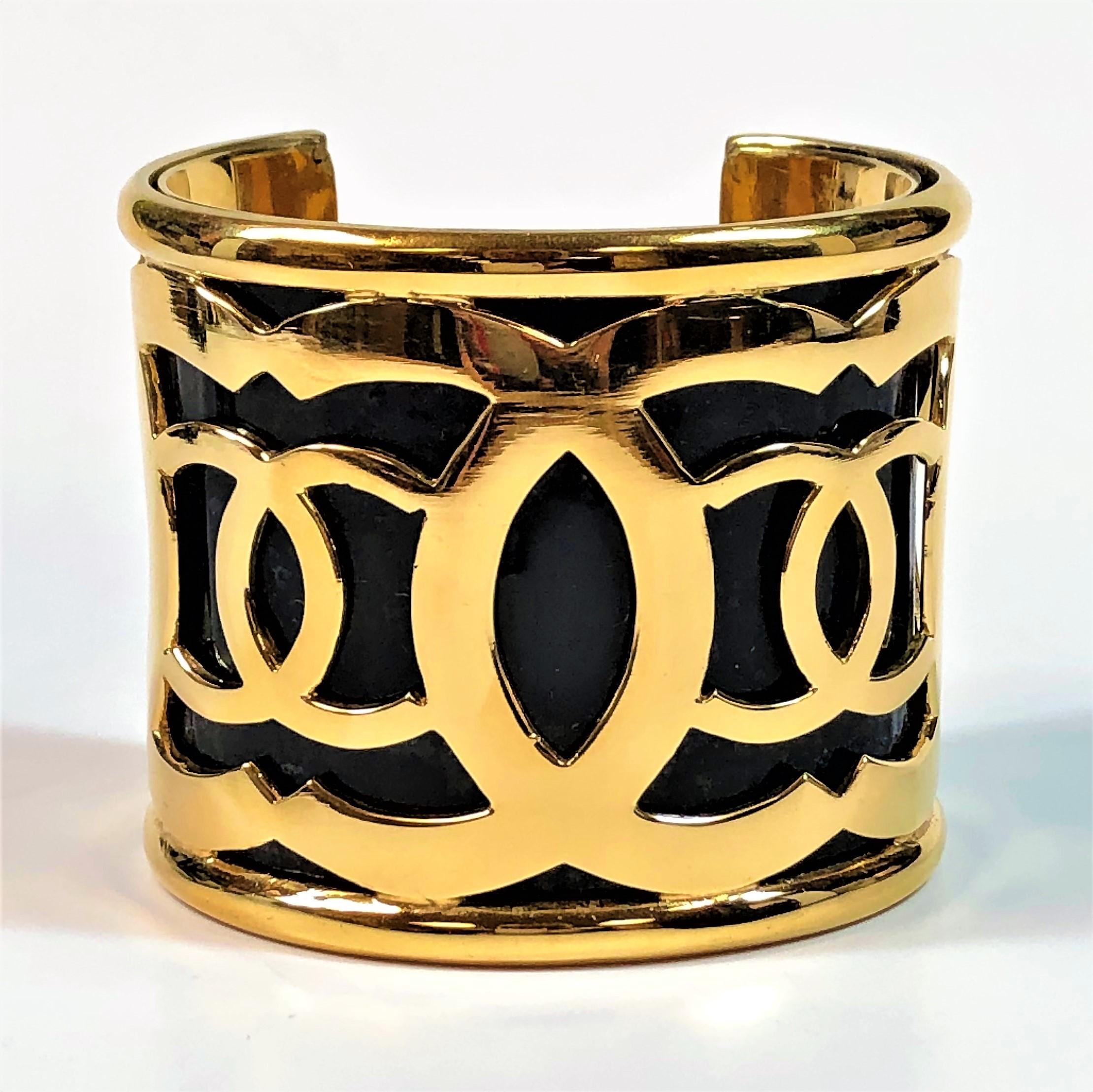 Chanel made this dramatic cuff in the mid 1980s. The gold tone CC logos cover the entire cuff over the black plastic background underneath. Open back design for ease of putting on and taking off. Measures 2  7/16 inches wide. Inside circumference is