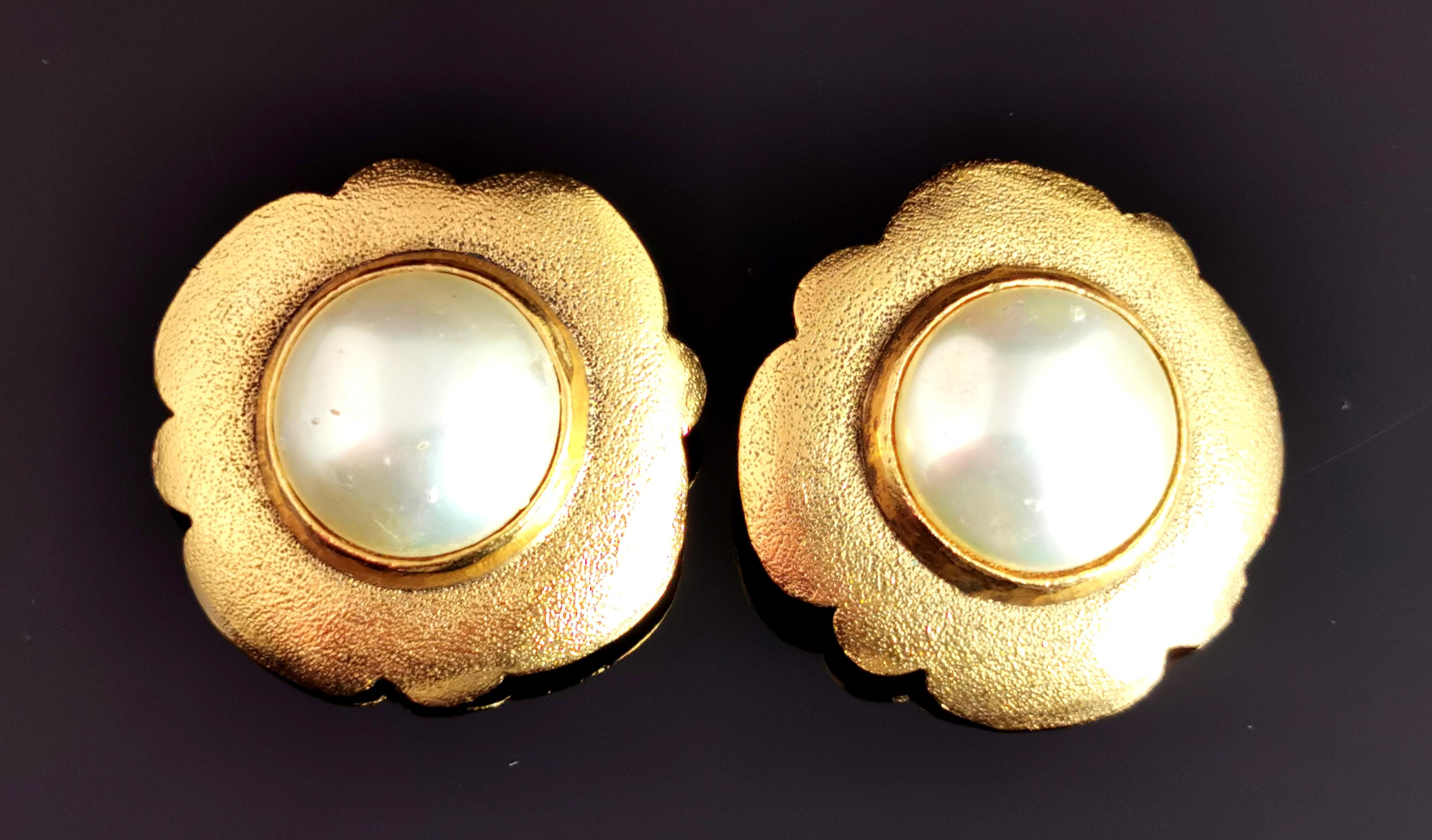 A fantastic pair of vintage Chanel clip on earrings.

A large pair of earrings in gold tone, lightly textured metal in an abstract floral shape.

Each earring is set with a large creamy lustrous faux pearl.

The earrings have a clip on fitting and