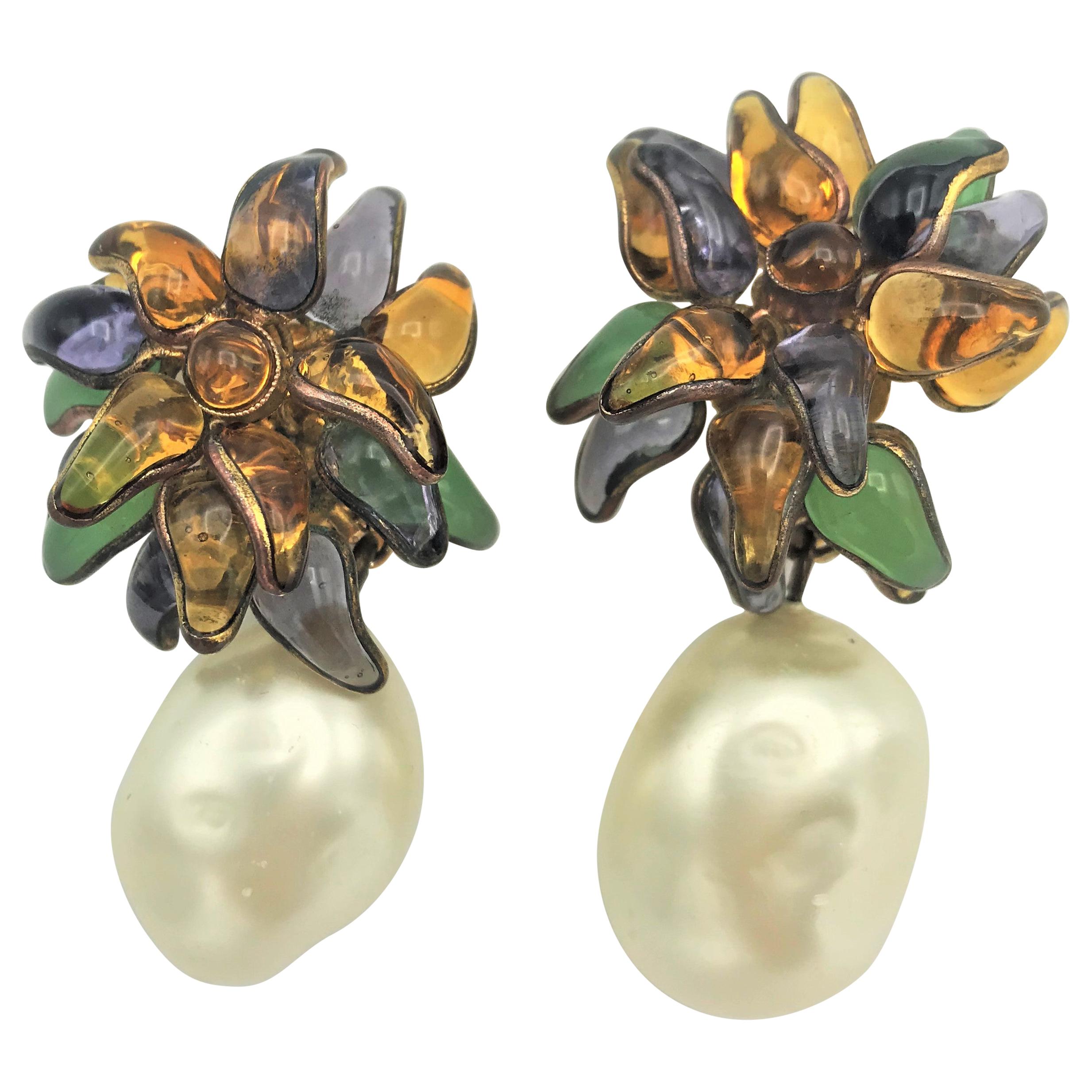 An extraordinary ear clip designed by Victoire de Castellane in 1984. The flower is handmade of pured glass with 17 small leaves in four different colors: purple, mint, yellow and brown. On the flower hangs a fantastic and huge faux pearl which is