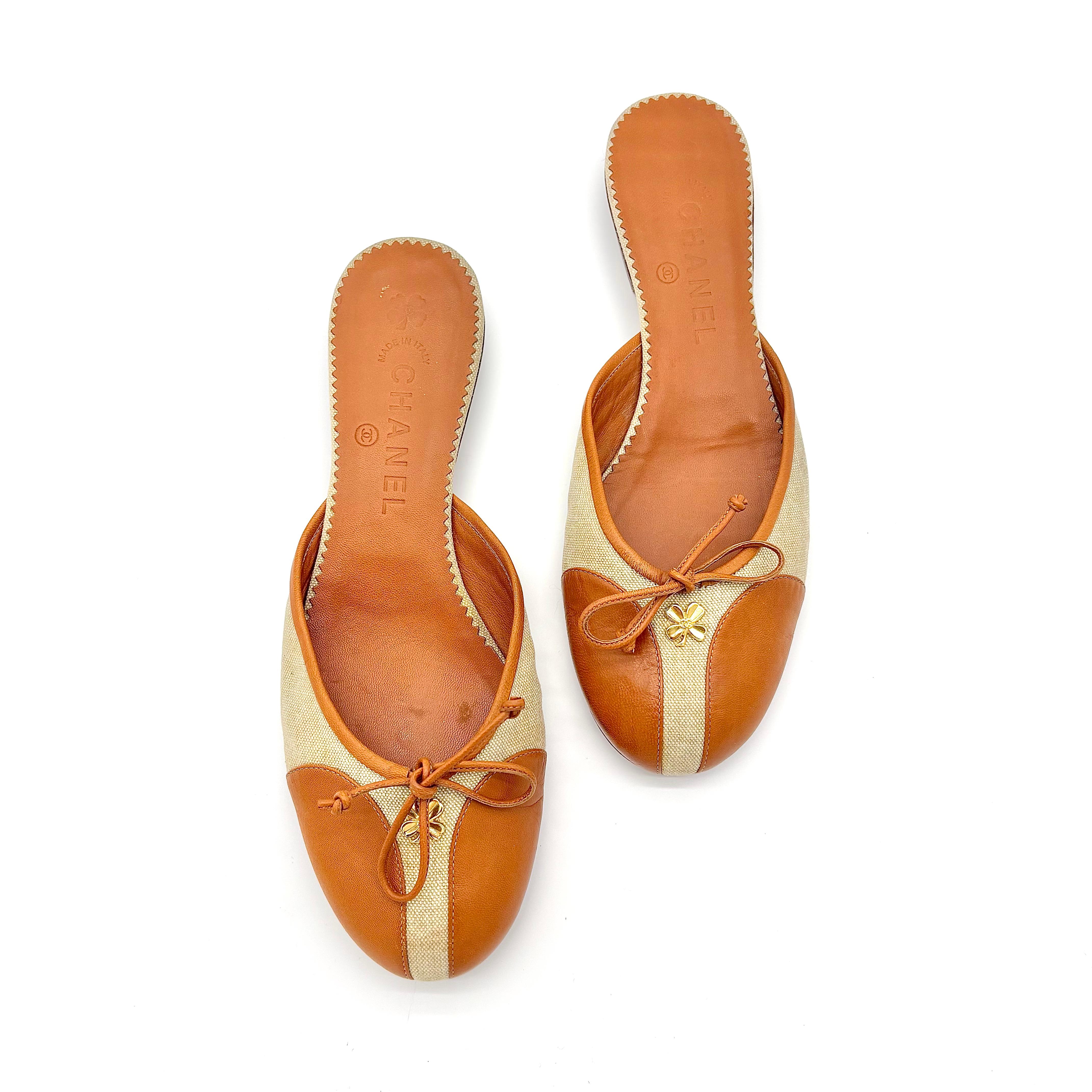 Mules in pelle di Chanel con fiocco a forma di quadrifoglio impreziosito da tela
Colore Marrone / Crema
Taglia 38.5EU
Tomaia in tela e pelle
Suola in cuoio
Dettaglio fiocco
Abbellimento a quattro foglie di trifoglio con finitura dorata 
Stile slip