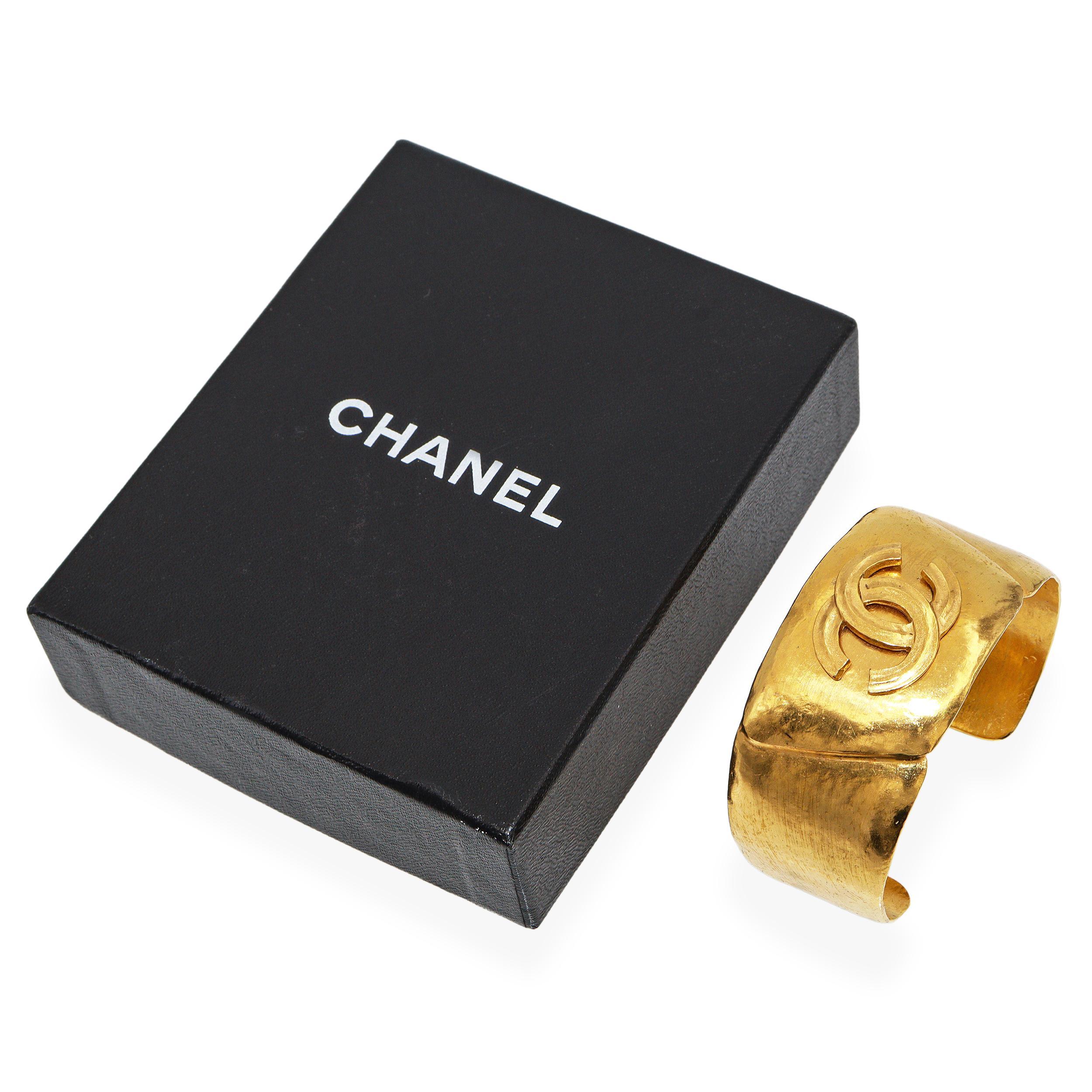Una llamativa pulsera brazalete vintage Chanel con acabado dorado que muestra el emblemático logotipo CC entrelazado en atrevido relieve. Este diseño escultural, acabado a mano, presenta la superficie dorada texturizada característica de Chanel y