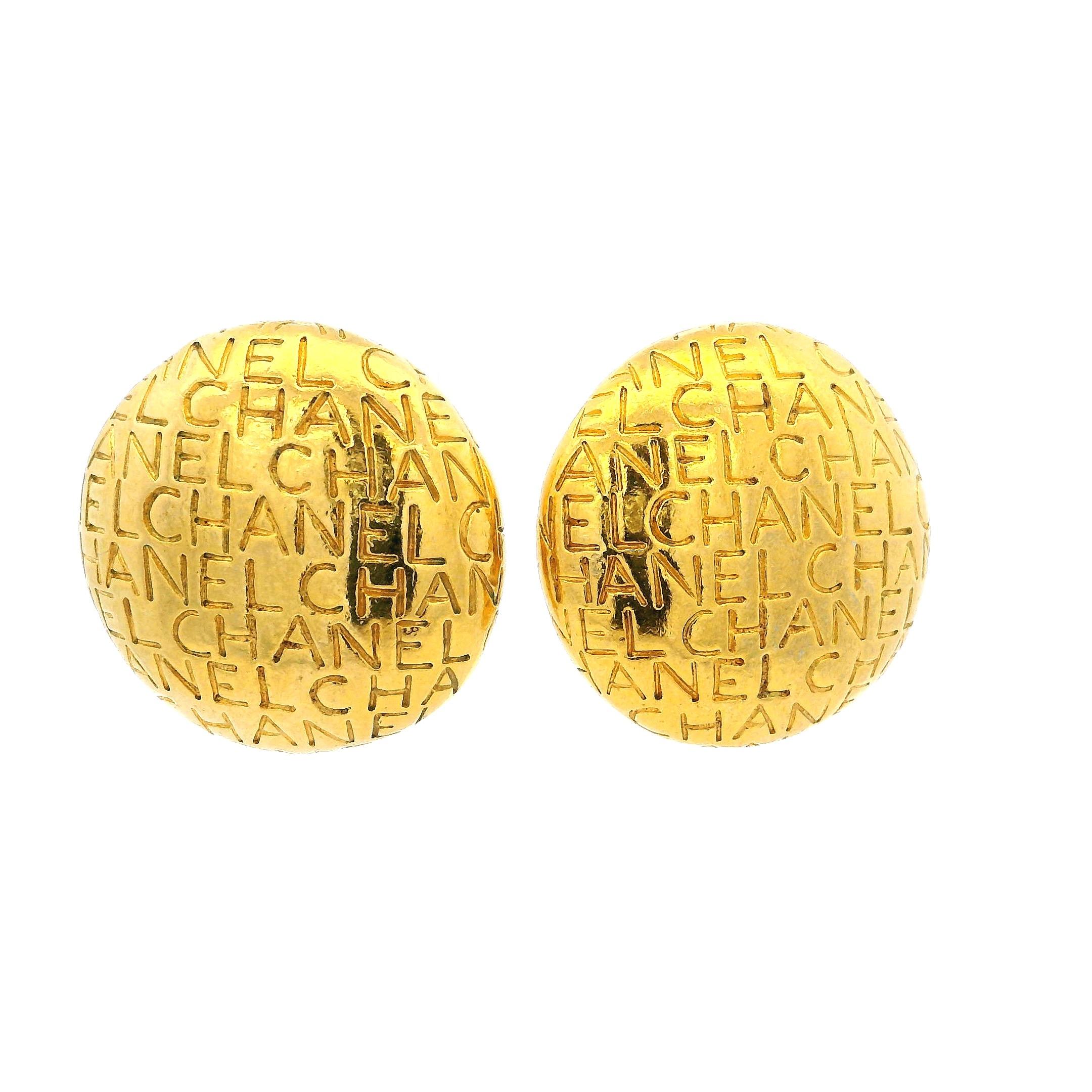 Esempio di gioielli Chanel degli anni '90, questi audaci orecchini a clip sono una celebrazione dell'iconico marchio della Maison e del glamour parigino. Realizzato in metallo placcato oro, ogni orecchino a cupola da 1,2 pollici è impreziosito da un