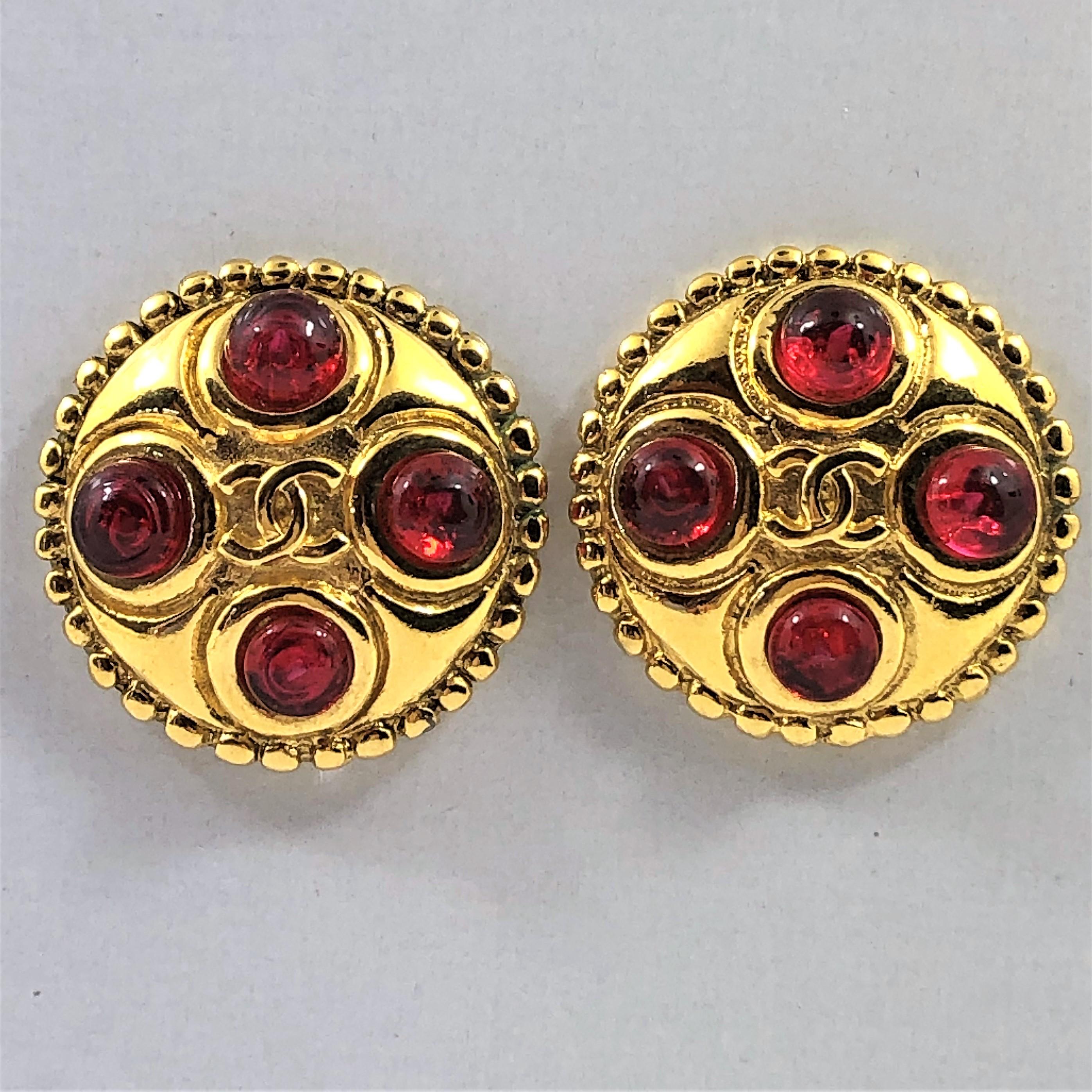 These lovely gold tone Chanel Red Gripoix earrings are from the 1986 season. They 
have the CC logo in the center surrounded by 4 bright red Gripoix cabochons.
They measure 1 3/16 inch in diameter. The clip on backs are firm. Marked CHANEL
2 CC 3