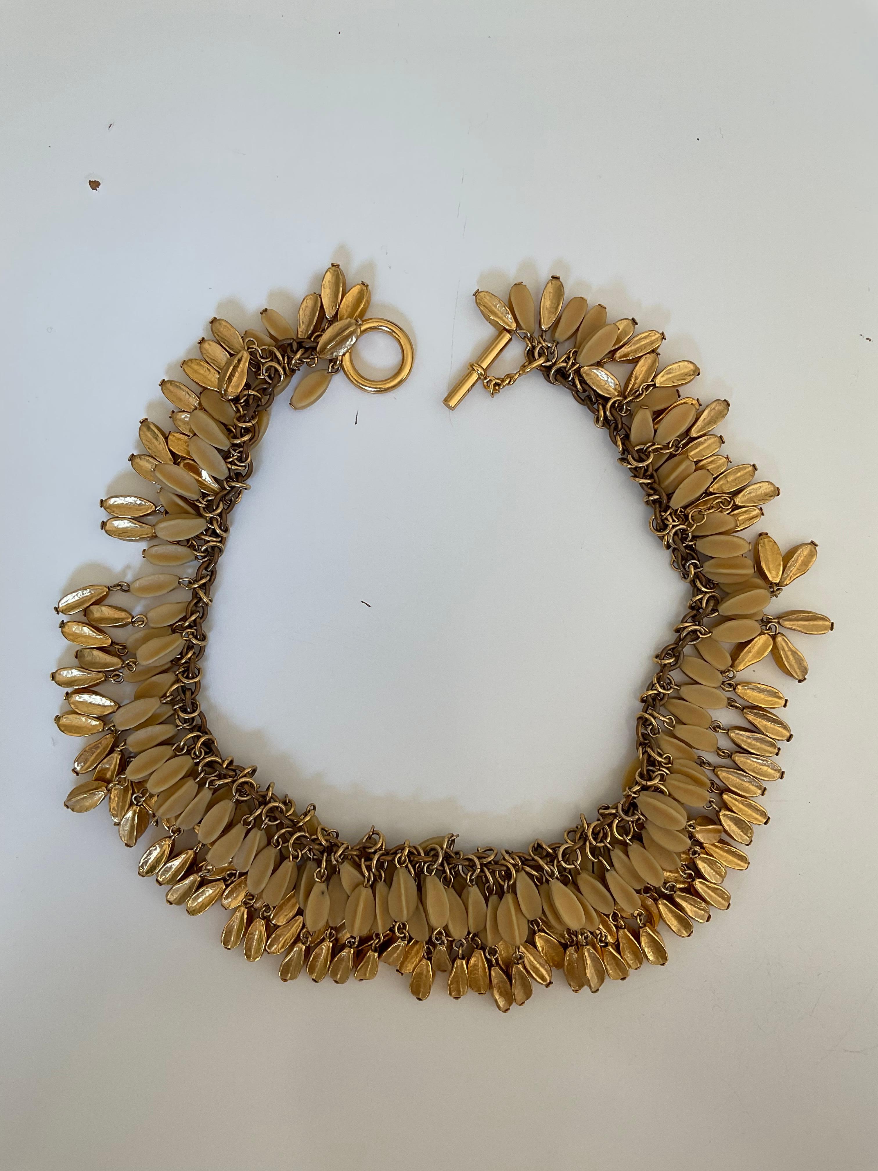 This rare necklace is a Vintage piece of the House of CHANEL from the 80's. The necklace is conceived with a gold-plated chain. It closes with a bar and a ring. All around the chain, there are tassels composed of ivory on the first row and gold