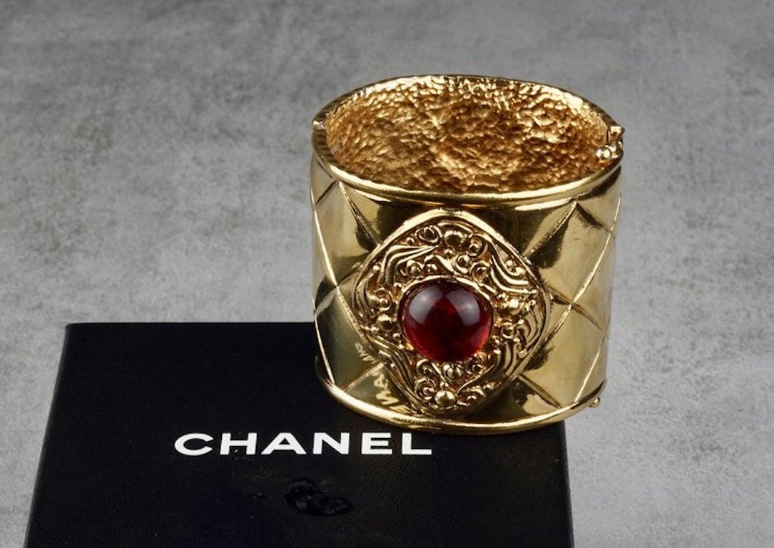 Vintage CHANEL Gripoix Quilted Cuff Bracelet

Measurements:
Height: inches (5.7 cm)
Inner Circumference: 7.08 inches (18 cm)

Features:
- 100% Authentic CHANEL.
- Quilted wide cuff bracelet.
- Orange gripoix/ poured glass at the centre.
- Clamper