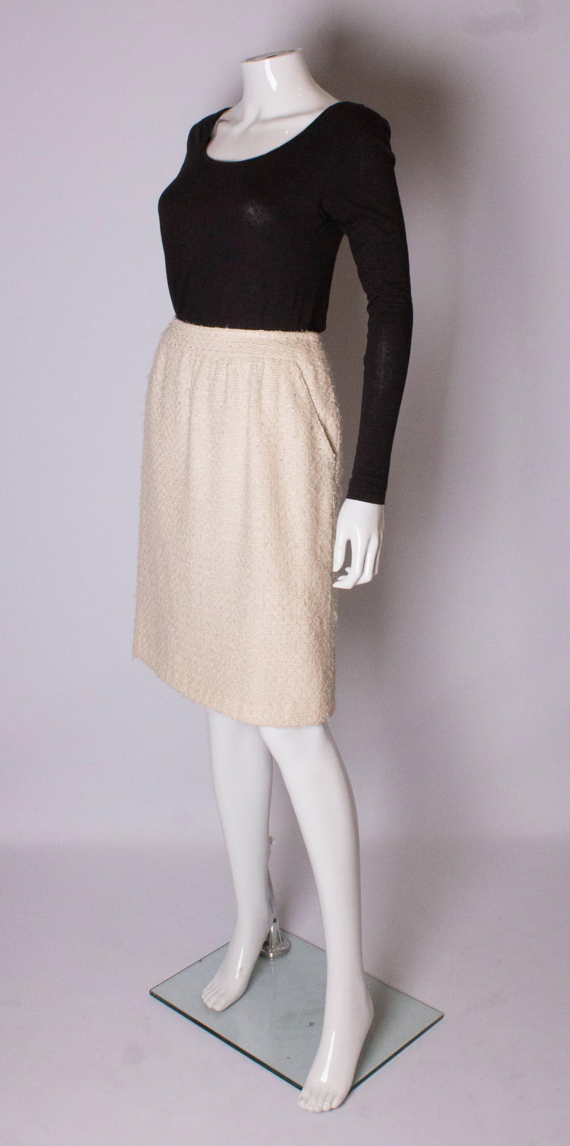 A classic ivory boucle skirt by Chanel  Boutique. The skirt is made of a wool and silk mix with a silk lining, and  has a central back zip and two  pockets at the front. The skirt has a 4'' hem.