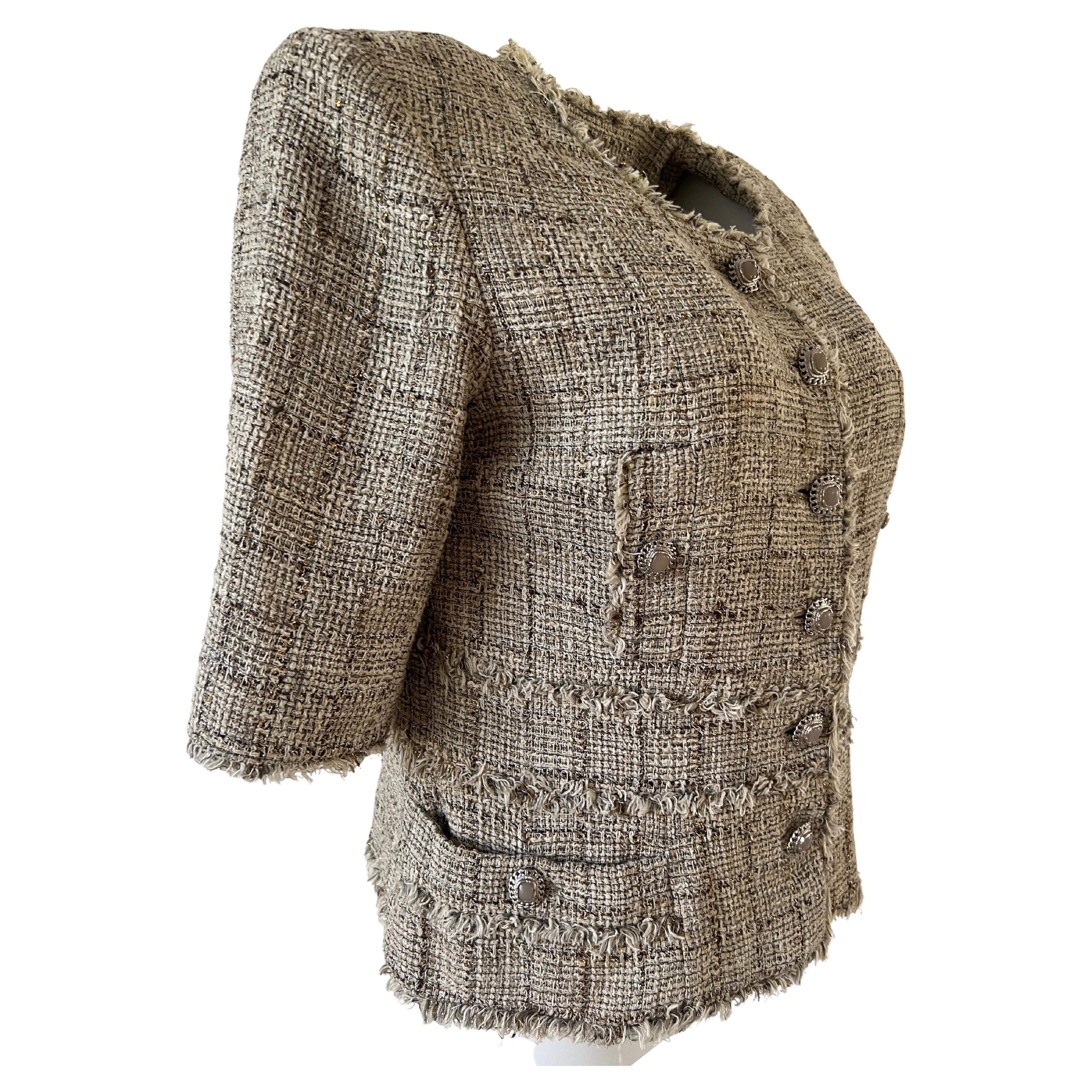 Beige Chanel jacket in cotton tweed blend of material with golden threads in the weaving. On the front, four pockets each enhanced with their button. The waist is underlined by a yoke. the whole braided by the threads of the weaving. Six buttons