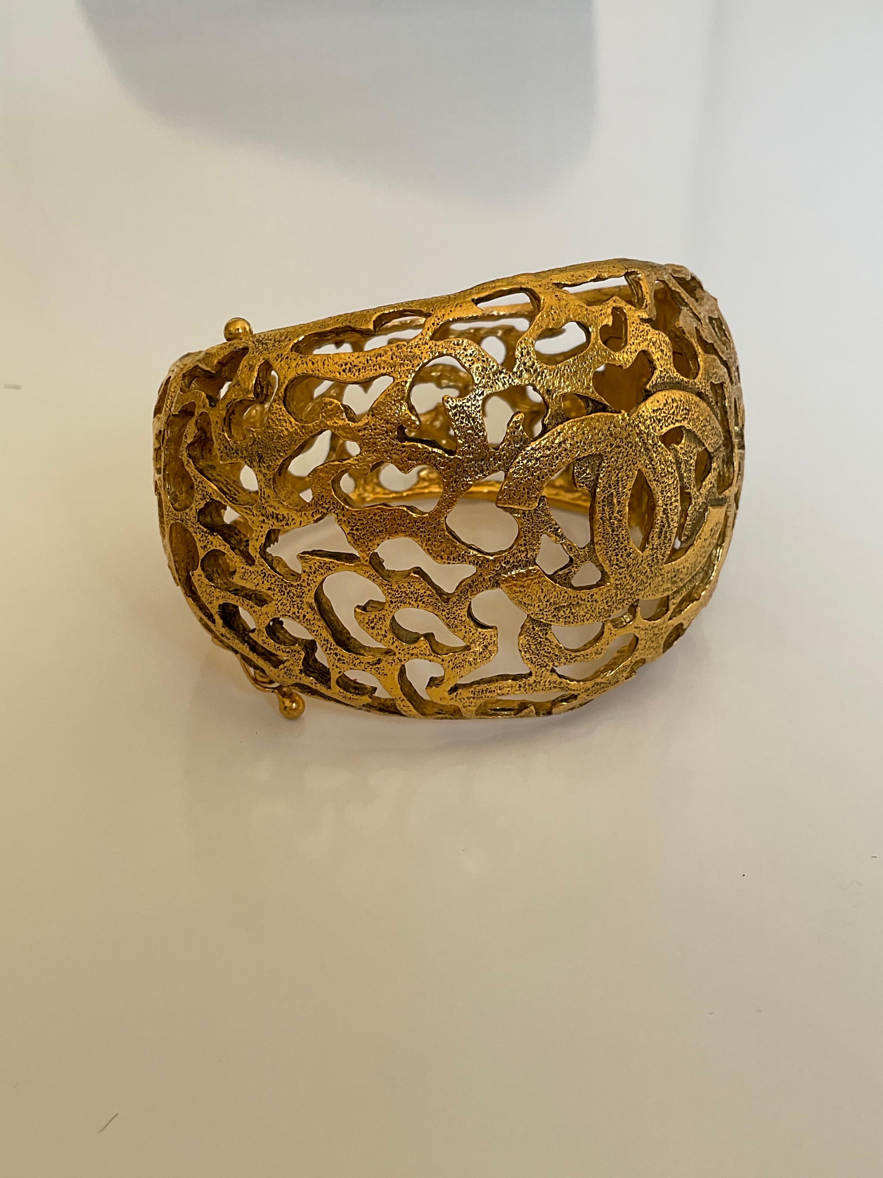 Diese goldfarbene Manschette von CHANEL im Vintage-Stil ist ein unverzichtbares Stück für Ihre Sammlung. Dieses bemerkenswerte Armband mit dem ikonischen, ineinandergreifenden CC-Logo des Hauses Chanel zeichnet sich durch ein kompliziertes Design