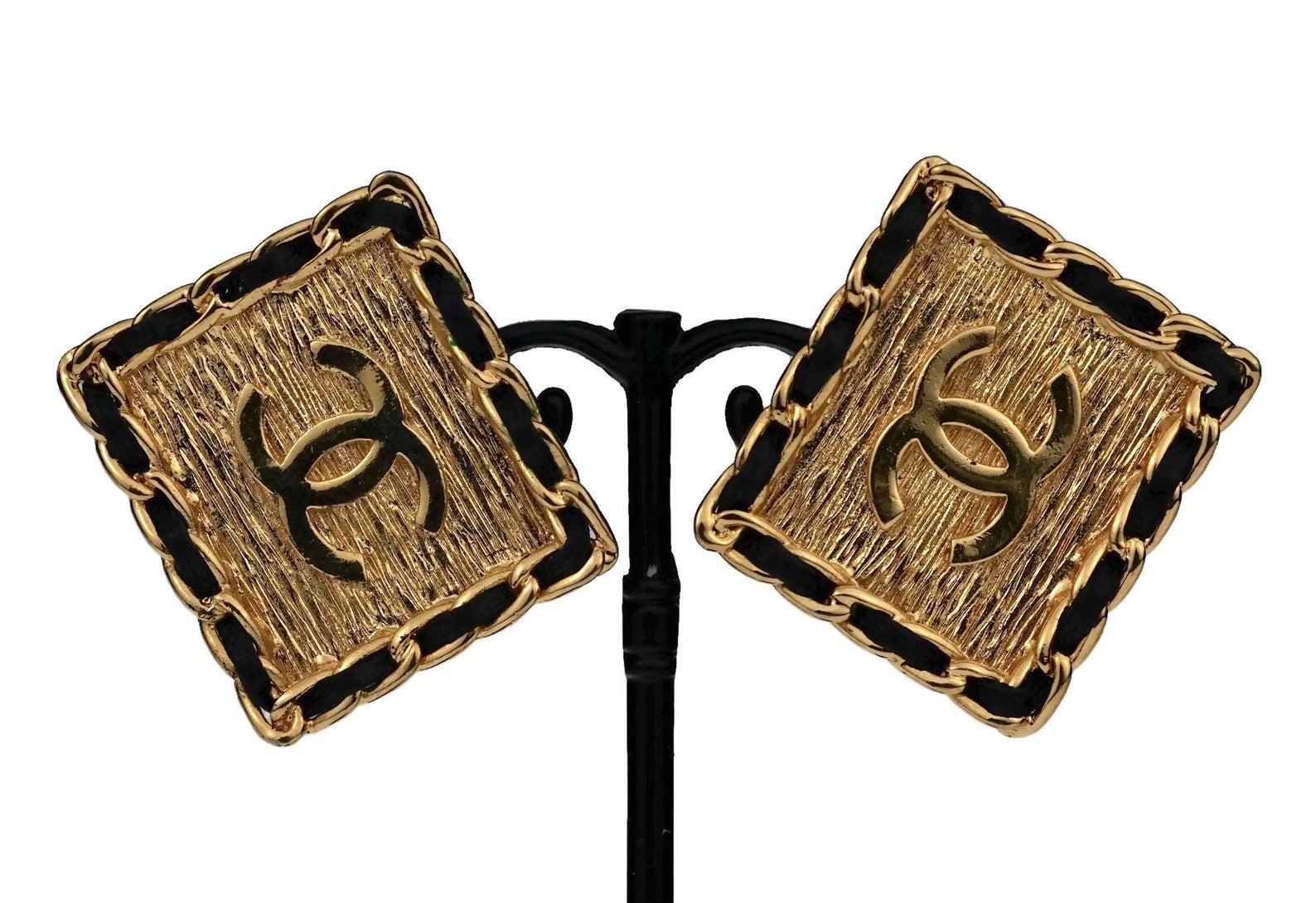Vintage CHANEL Logo Chain Leather Square Earrings

Measurements:
Height: 1.30 inches (3.3 cm)
Width: 1.53 inches (3.9 cm)
Weight per Earring: 13 cm

Features:
- 100% Authentic CHANEL.
- Chanel classic leather chain earrings.
- Rectangular form with