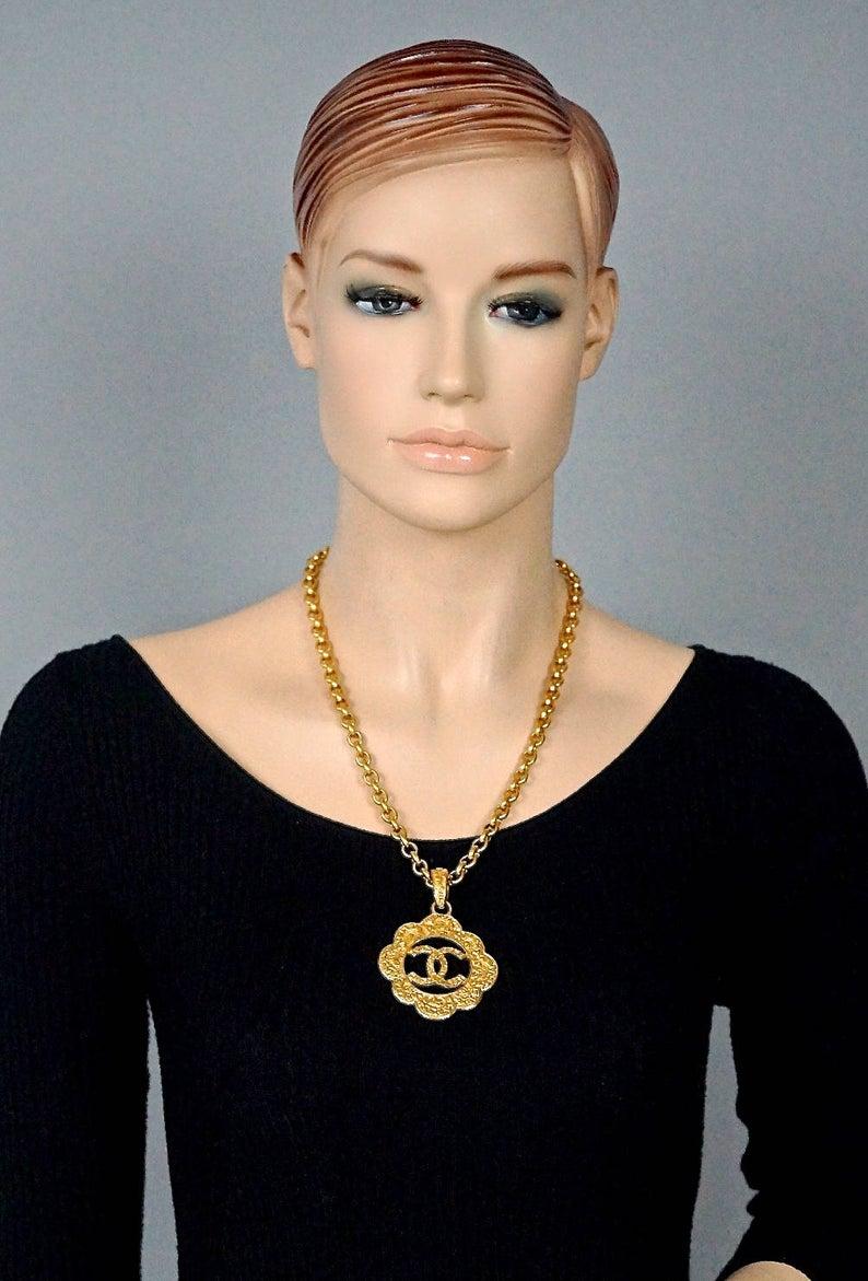 Vintage CHANEL Logo Cutout Flower Necklace

Measurements:
Height: 2.95 inches (7.5 cm) with the pendant bail
Width: 2.12 inches (5.4 cm)
Length: 22 inches (56 cm)

Features:
- 100% Authentic CHANEL.
- Cutout flower with embossed Chanel all over and 