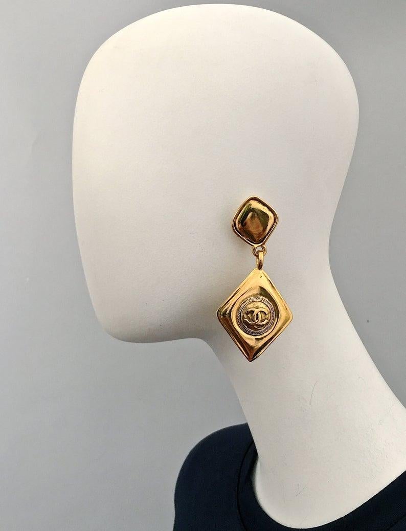 Vintage CHANEL Logo Diamond Shape Dangling Earrings

Measurements:
Height: 3.15 inches (8 cm)
Width: 1.57 inches (4 cm)

Features:
- 100% Authentic CHANEL.
- Dangling earrings in double diamond shape with CC Logo at the centre.
- Clipback