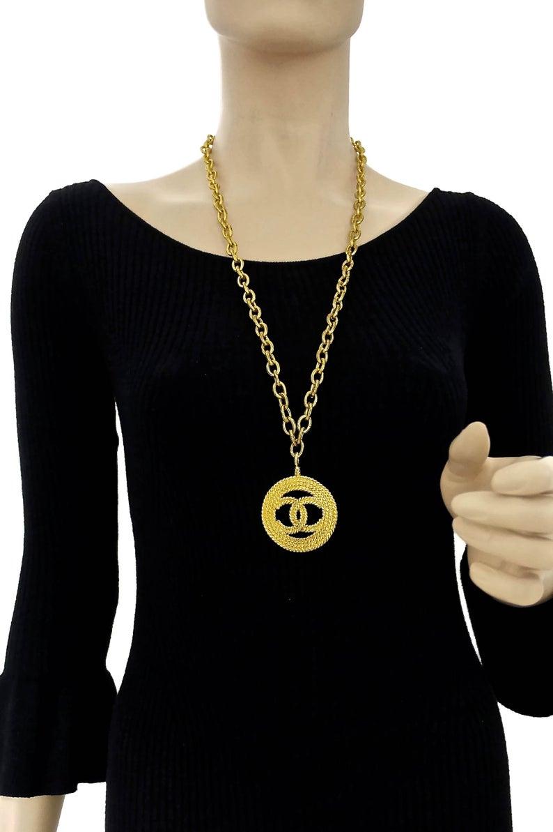 Vintage CHANEL Logo Medallion Necklace

Measurements:
Height: 2 inches (5cm)
Width: 2 inches (5cm)
Chain: 32 inches (81.28 cm)

Features:
- 100% Authentic CHANEL.
- Long textured chain and pendant in gold tone.
- Pendant has braided/ rope-like