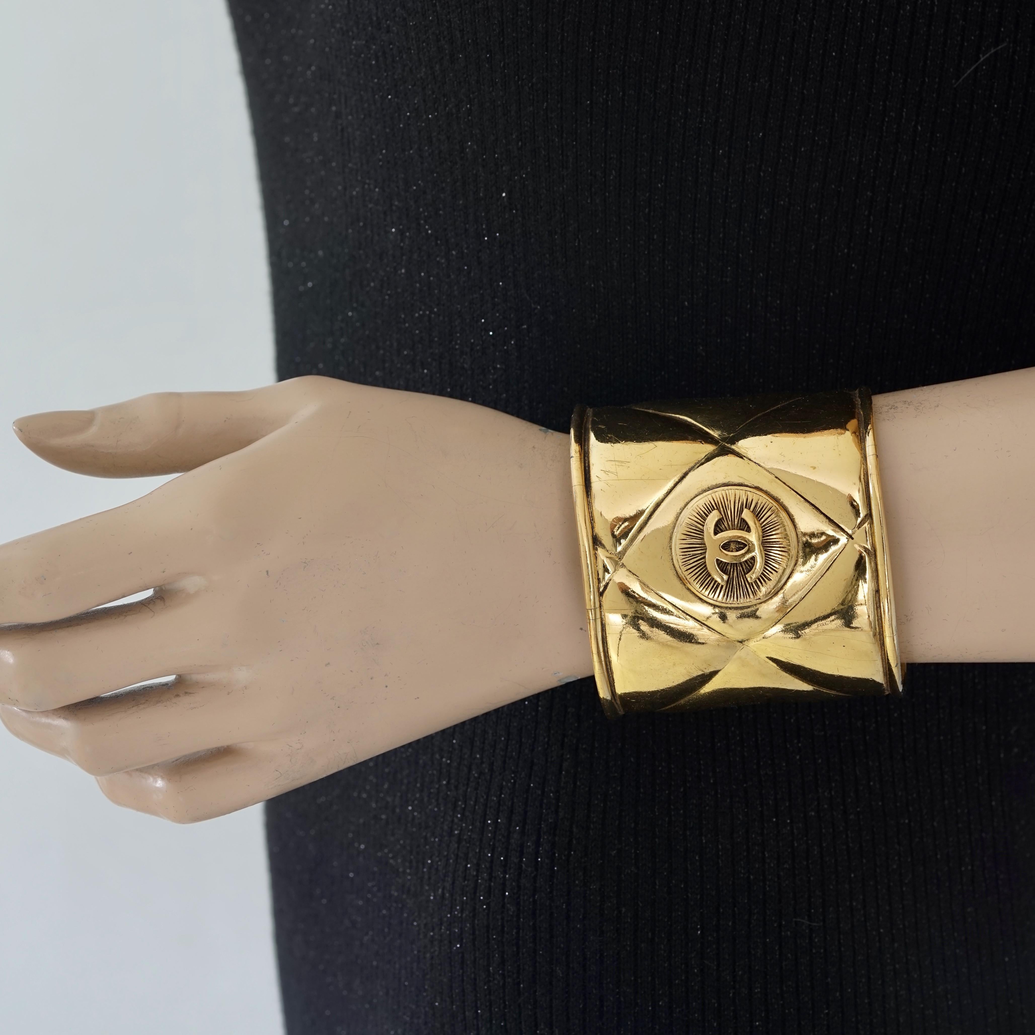 Vintage CHANEL Logo Medallion Quilted Cuff Bracelet

Measurements:
Height: 2.55 inches (6.5 cm)
Inner Circumference: 7.08 inches (18 cm) opening included

Features:
- 100% Authentic CHANEL.
- Quilted wide cuff bracelet with CC logo medallion at the