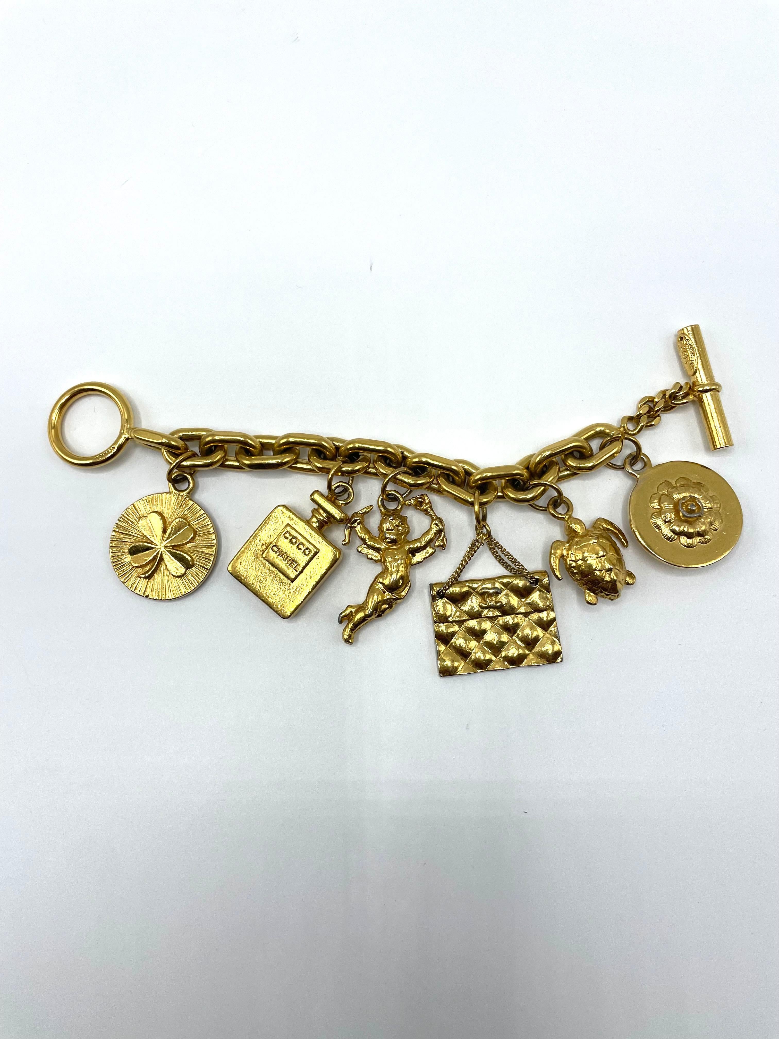 Chanel bracelet with a good luck charm. Each of the seven charms is distinct and unusual. Seven charms, including a camellia flower, a turtle, a Chanel purse, cupid, a perfume bottle, a shoe, and a clover, are tied to a gold-tone chain link. 
All of