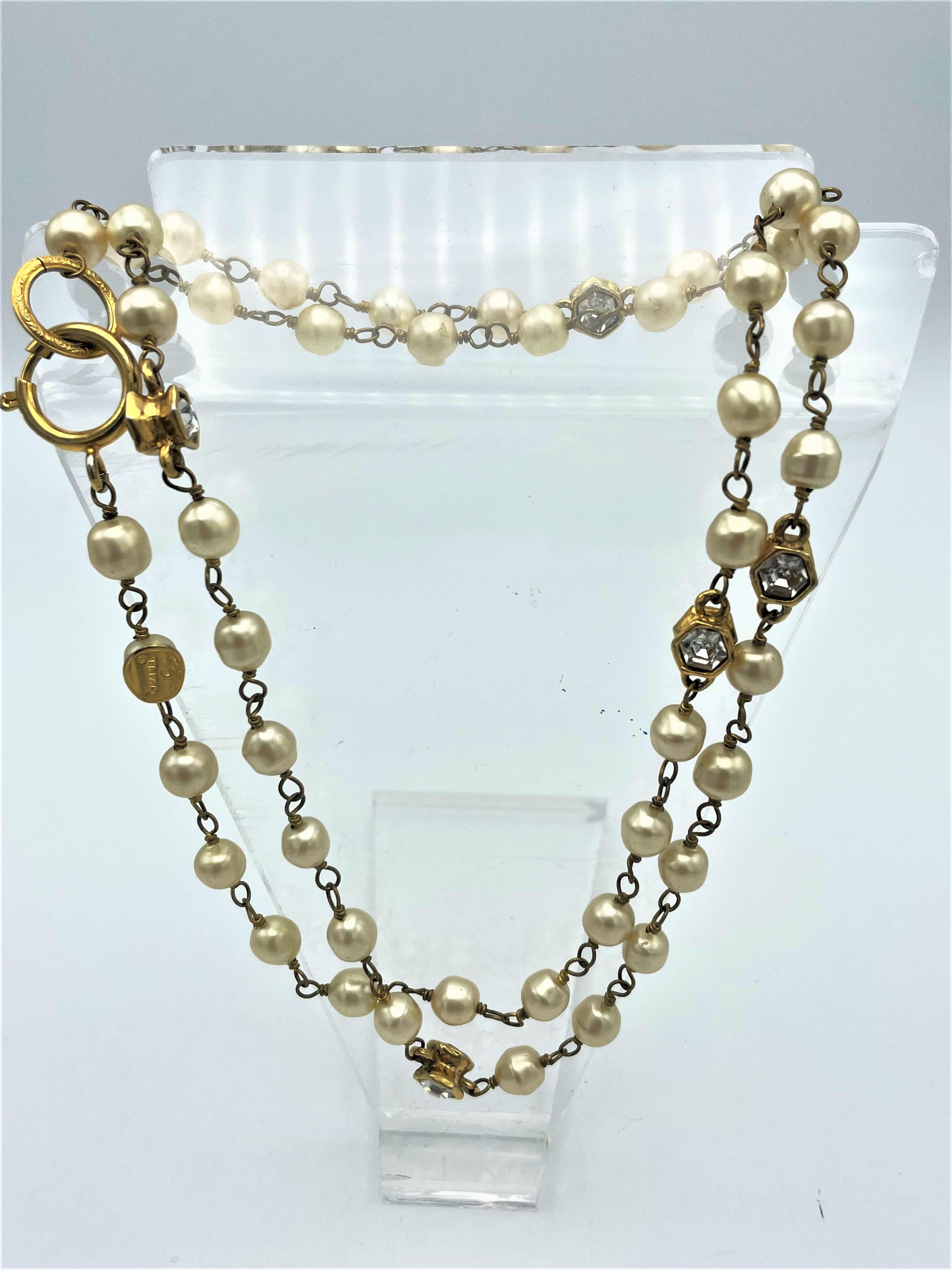 About
Chanel necklace with  false pearls and 5 hexagonal golden shapes with cut rhinestones, double-sided. 5 polished rhinestones on both sides, 10 mm high and width. Great to wear on any occassion. 
Measurement:
Length:  0,94 cm
Pearl size: 0,76 cm