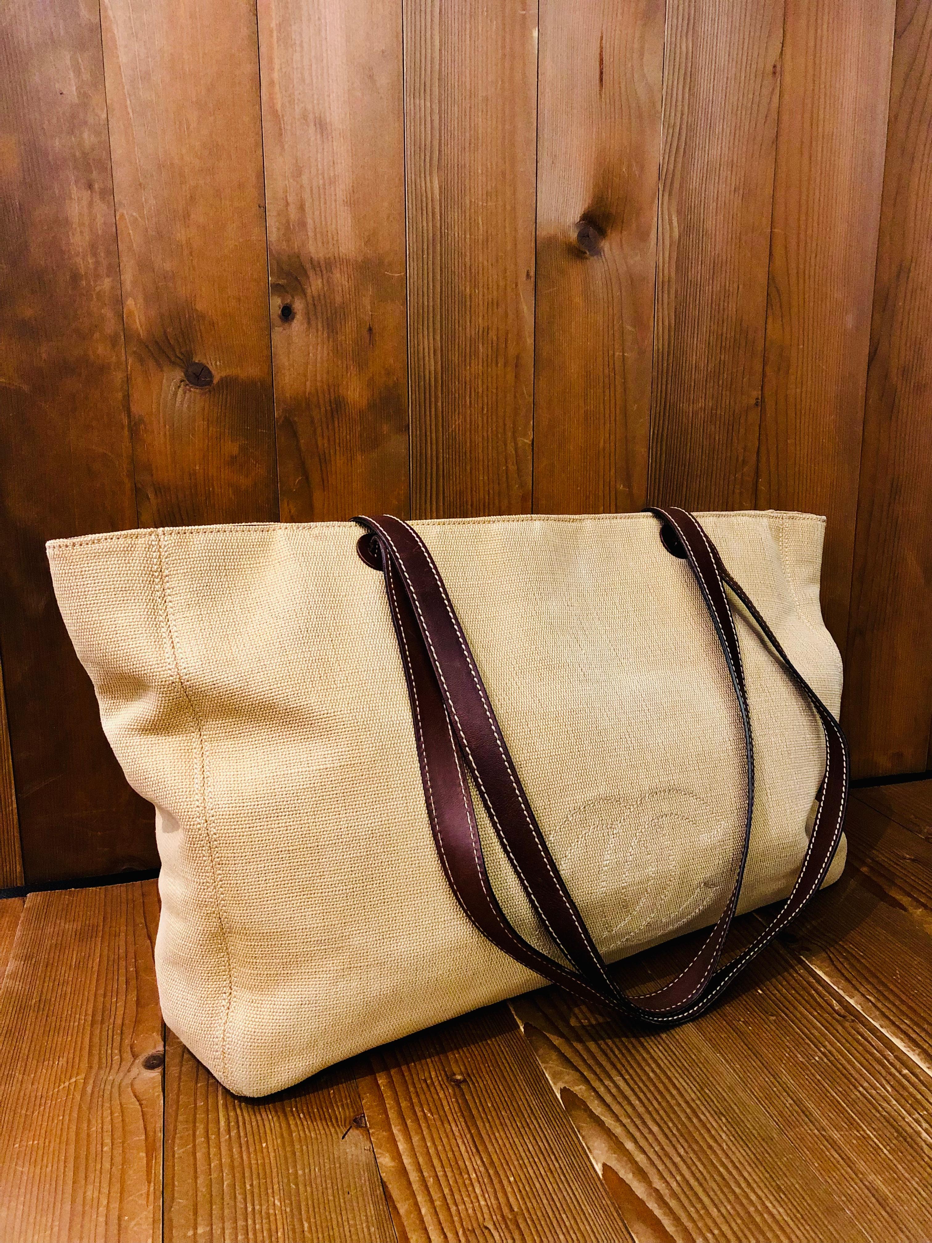 Ce sac fourre-tout surdimensionné de Chanel est confectionné en lin beige et doté de deux anses en cuir de veau. Les doubles fermetures magnétiques dissimulées s'ouvrent sur un intérieur spacieux en tissu marron foncé, doté de deux poches zippées.