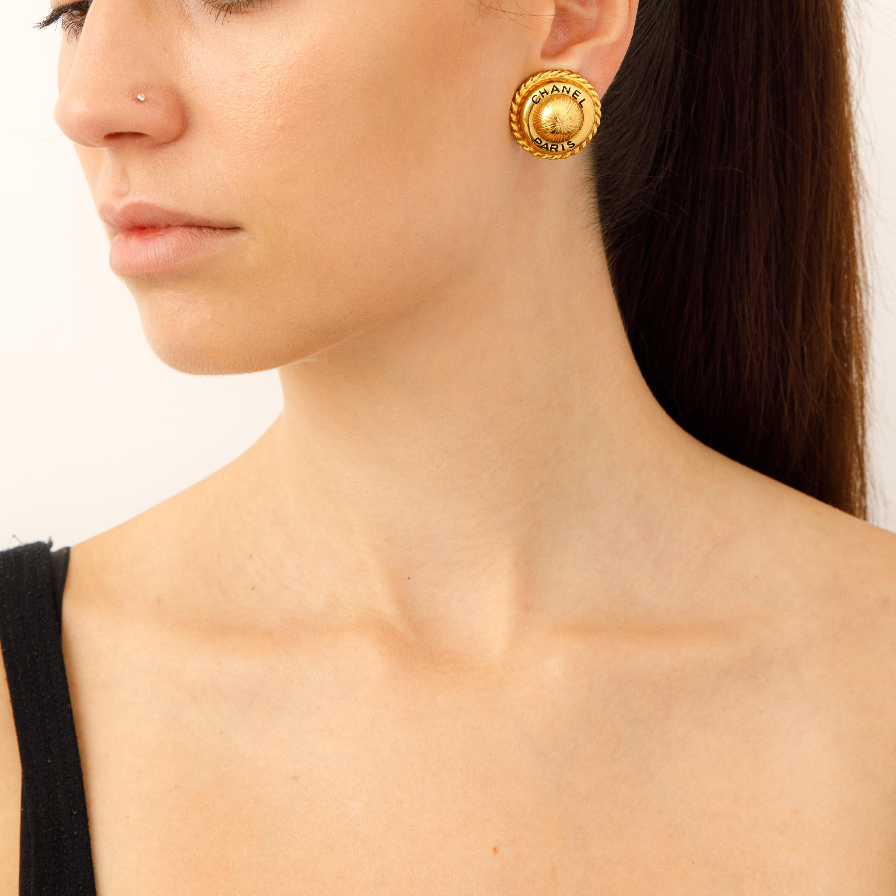These exquisite Vintage Chanel Paris Button Earrings embody the timeless elegance and exquisite craftsmanship of the iconic French luxury brand. Crafted in luxurious gold-tone metal and featuring the classic signed Chanel logo, these earrings will