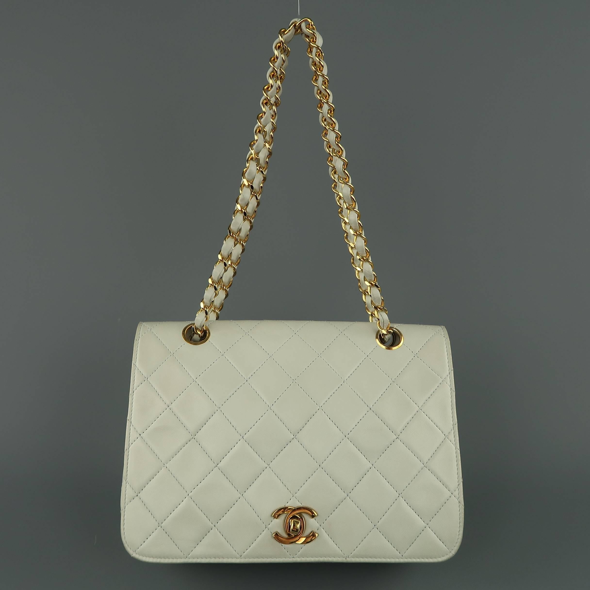 Vintage 1980's CHANEL bag comes in pastel minty blue quilted leather and features a flap with gold tone CC twist closure, white leather interior with pockets, and gold tone leather woven chain strap with grommets. Discolorations and wear throughout