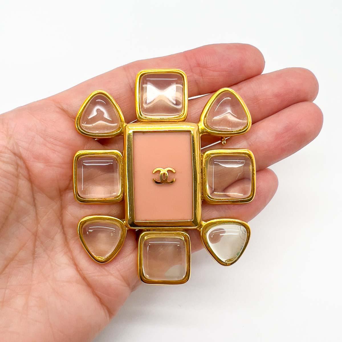 Un precioso broche vintage grande de Chanel. La inversión con estilo perfecta. Con deliciosas piedras de cristal de roca de imitación (resina) que rodean una placa rosa salmón (resina) que lleva el logotipo de la Casa Chanel con la C entrelazada por