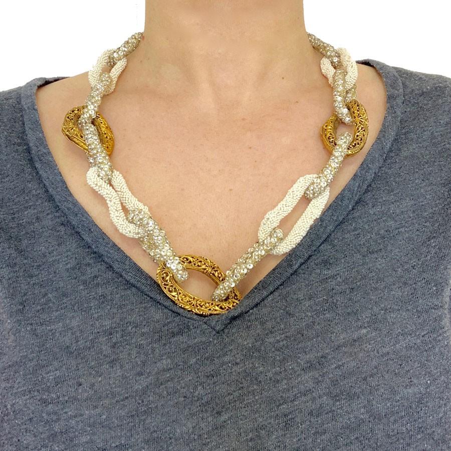 This stunning piece comes directly from 1996 ! A real piece of art mixing several rings made of chiseled gold tone metal, withe small pearls, and transparent crystal pearls sewn with a gold thread. This necklace is in very good condition, its length