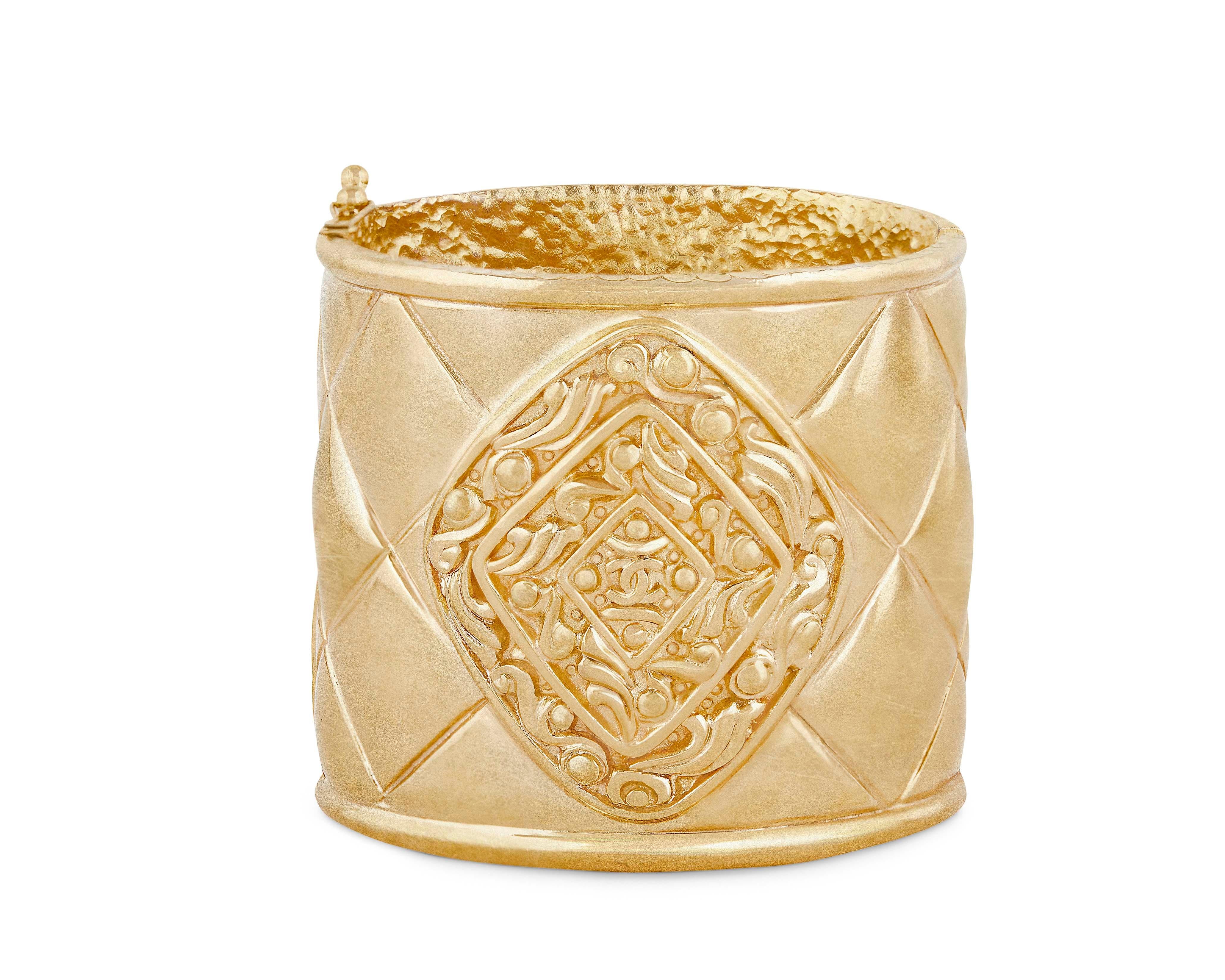 Vintage Chanel Matelasse hinged cuff bracelet in gold plate from the 1980s.  This collector's item features the signature Chanel quilted pattern all around with a central decorative Byzantine medallion with the iconic interlocking CC logo.  Bracelet