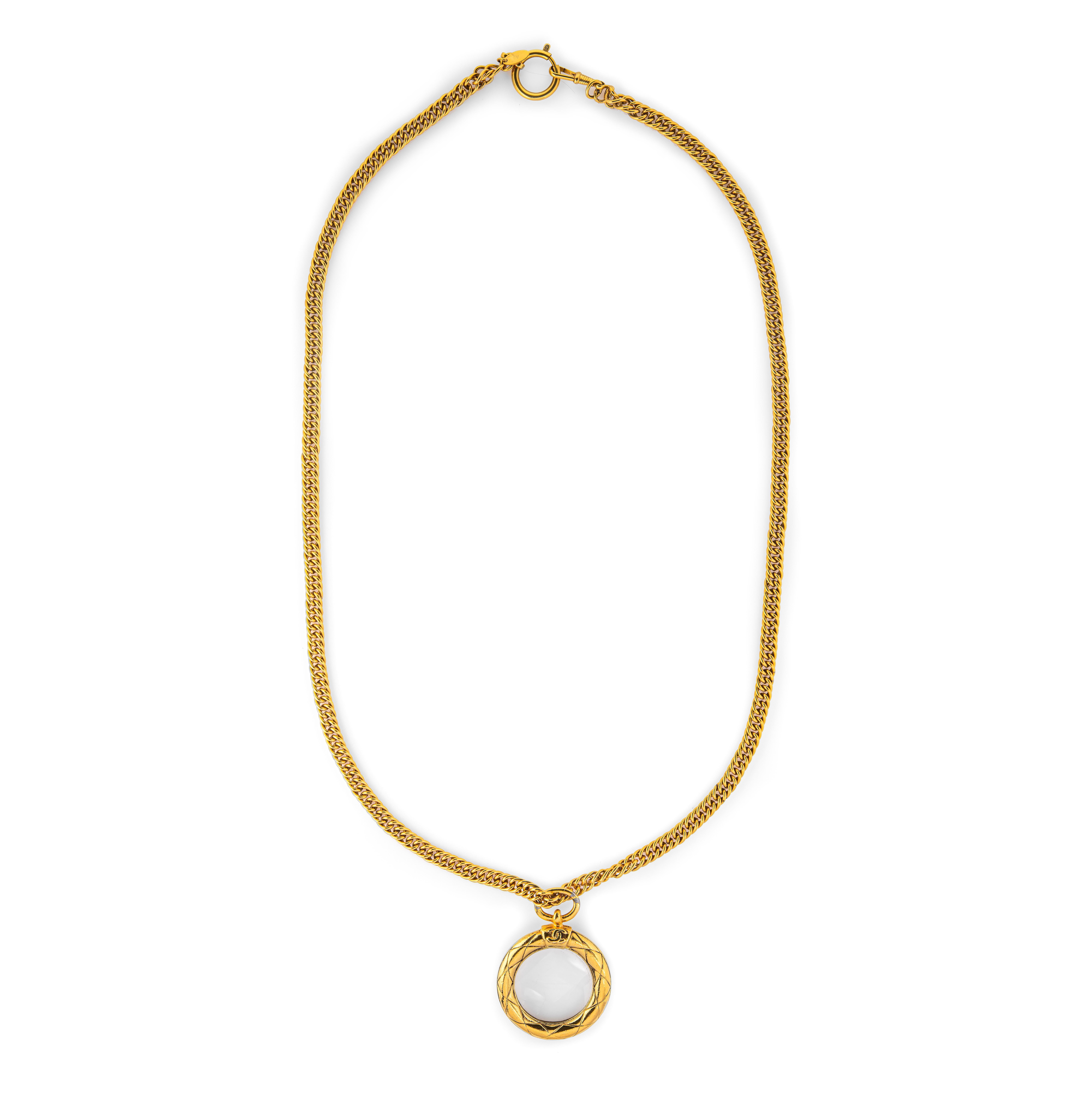 Vintage Chanel magnifying glass necklace crafted in yellow gold tone (circa 1980s). 

The long 36 inch curb link chain terminates to the quilted CC logo magnifying glass pendant. The substantial chain is 7.5mm wide (0.29 inches). 

The necklace is