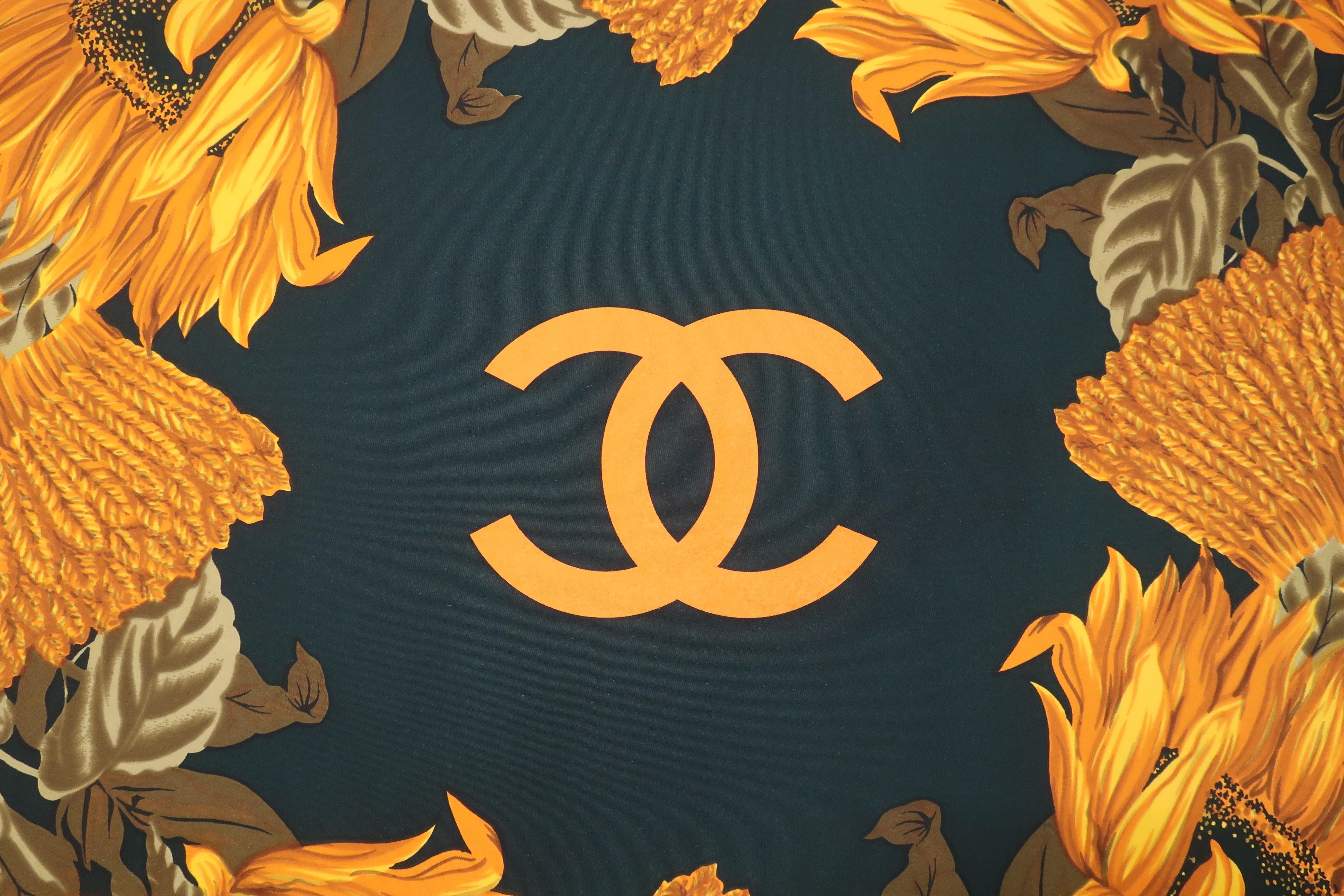 Chanel blends the iconic double 'C' logo with a brilliant sunflower pattern in rich autumnal colors to create a classic silk hand rolled scarf.  The dark green and golden yellows are the perfect compliment to everything from brown tweeds to grays. 