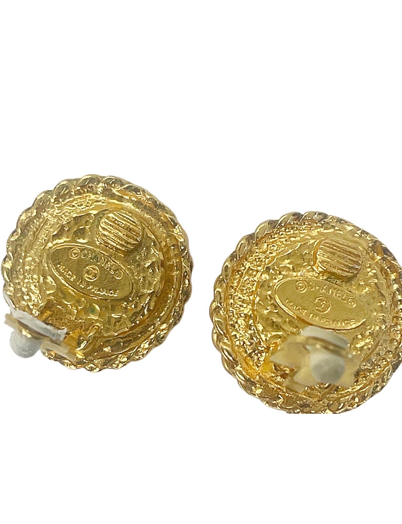 Eleva tu colección con estos llamativos pendientes de clip vintage de Chanel de la primavera de 1993, fabricados en Francia y con atrevidos cabujones de cristal rojo Gripoix enmarcados por el emblemático ribete de cuerda dorada retorcida de Chanel.