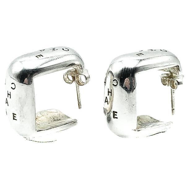 A stunning pair of solid sterling silver Vintage Chanel Silver Logo Earrings. Featuring a fabulously wearable huggie style hoop with CHANEL lettering. 

Since 1910 when Gabrielle 'Coco' Chanel opened her first boutique,  the House of Chanel boasts a